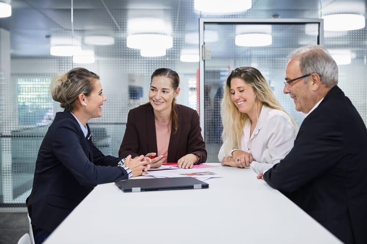 Team sitzt an hohen Tisch und bespricht sich