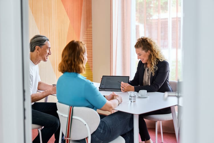 Arbeitssituation von 4 Personen mit Tablet und Laptop vor Flipchart