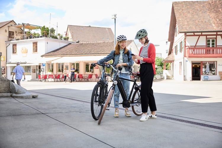 Deux femmes avec un vélo regardant sur un portable.