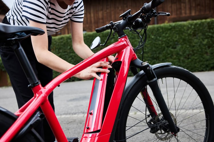 Giovane donna prende la batteria da rossa e-bike. 