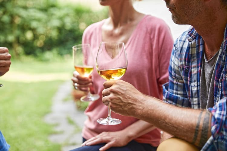 Symbolbild für Alkohol am Steuer in der Schweiz: Zwei Personen stossen mit Gläsern draussen an.
