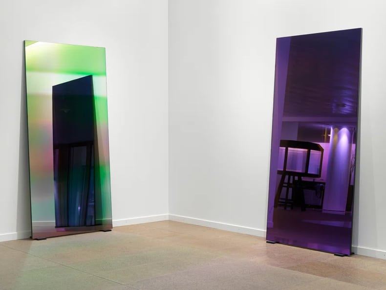 ein grüner und ein violetter Spiegel an der Wand in der Kunstausstellung der Mobiliar