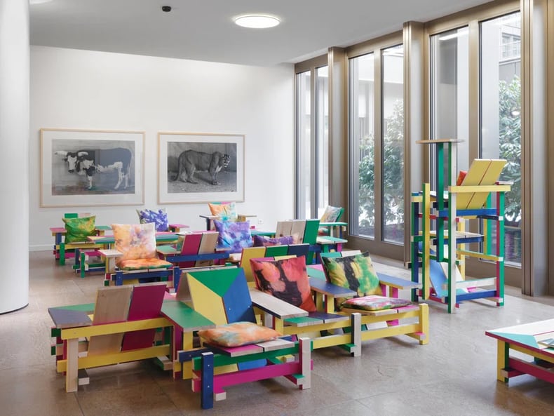 farbige Stühle vor einer Wand mit Bildern in der Kunstausstellung der Mobiliar