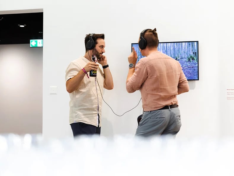 due uomini davanti allo schermo alla mostra Arte e sostenibilità presso la Mobiliare 