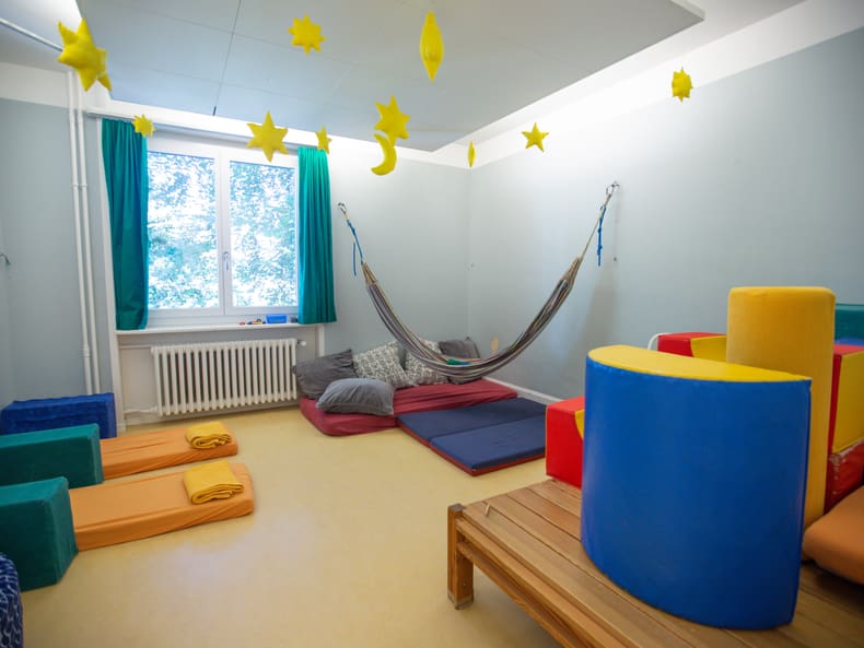 Ein buntes Zimmer mit Matratzen und einer Hängematte