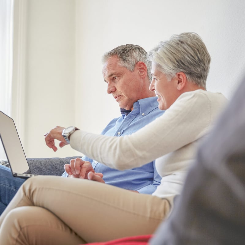 Coppia di anziani sul divano che guardano il laptop mentre fanno shopping online