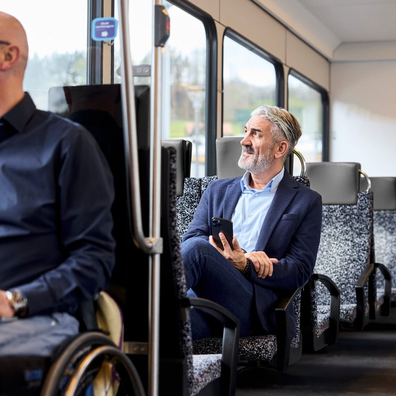 L’uomo in completo è seduto sul treno soddisfatto con lo smartphone in mano.