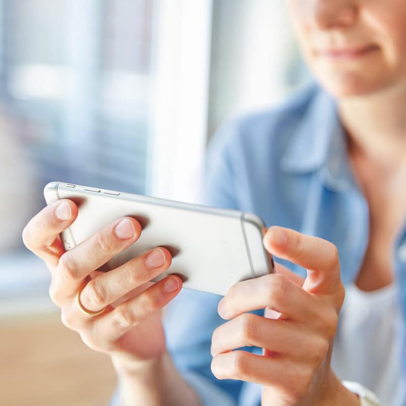 La donna utilizza uno smartphone argentato.