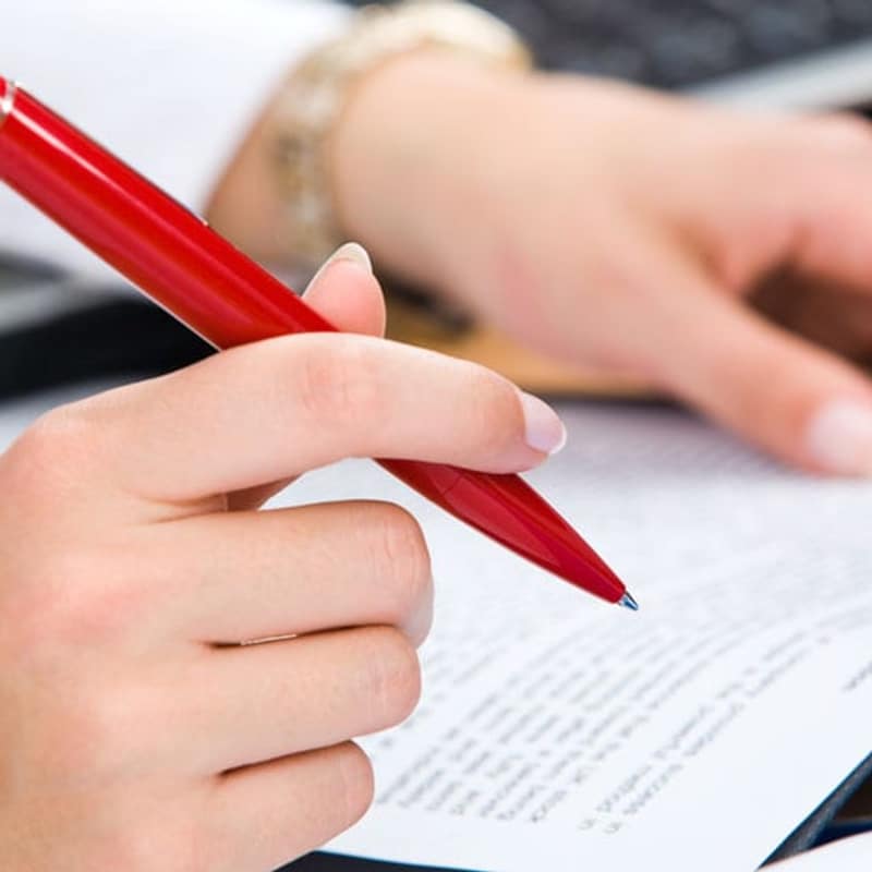 Une personne tenant un dossier et un stylo à la main