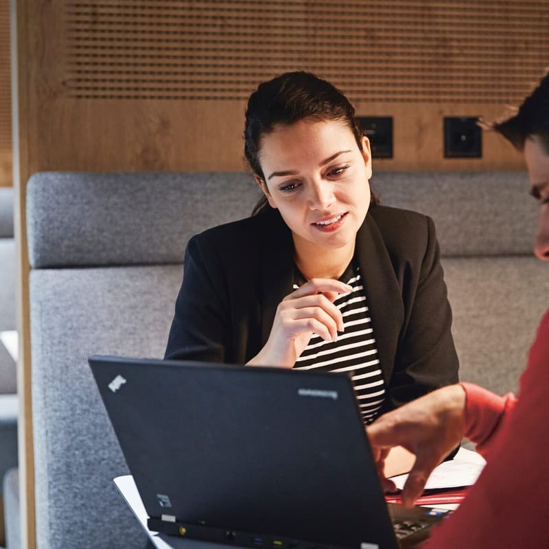 La femme et l’homme discutent de quelque chose et regardent ensemble l’écran d’un laptop.
