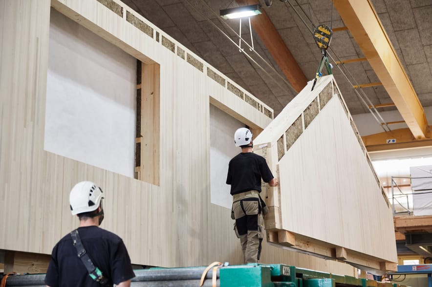 In una falegnameria due uomini montano una parte di casa.