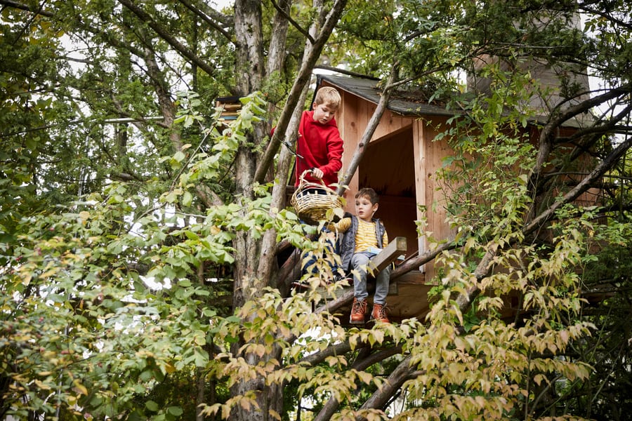 Zwei Buben sitzen in ihrem Baumhaus und spielen.