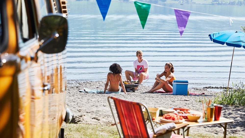 Junge Leute campieren am See.