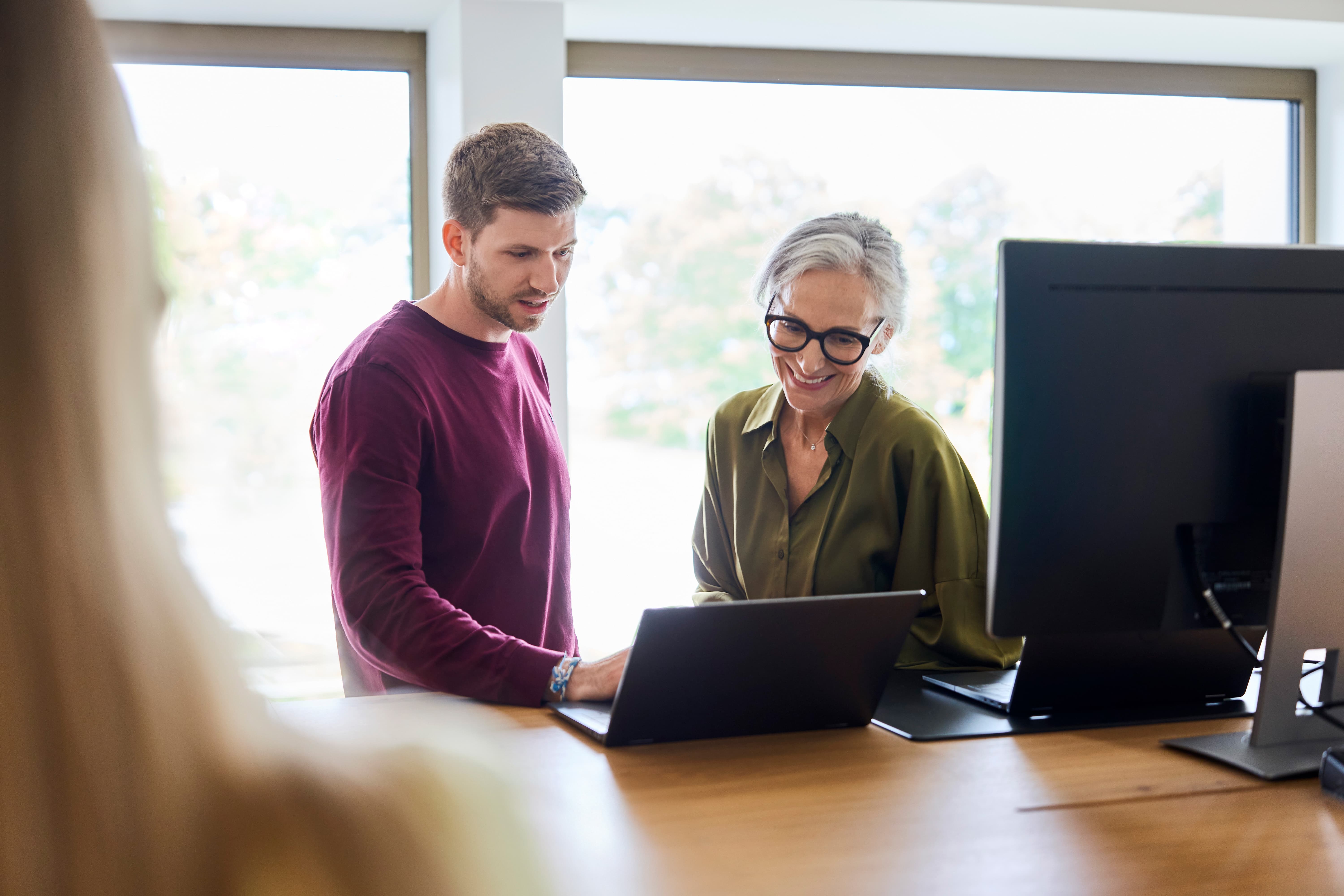 Zwei Mitarbeitende arbeiten an Laptop