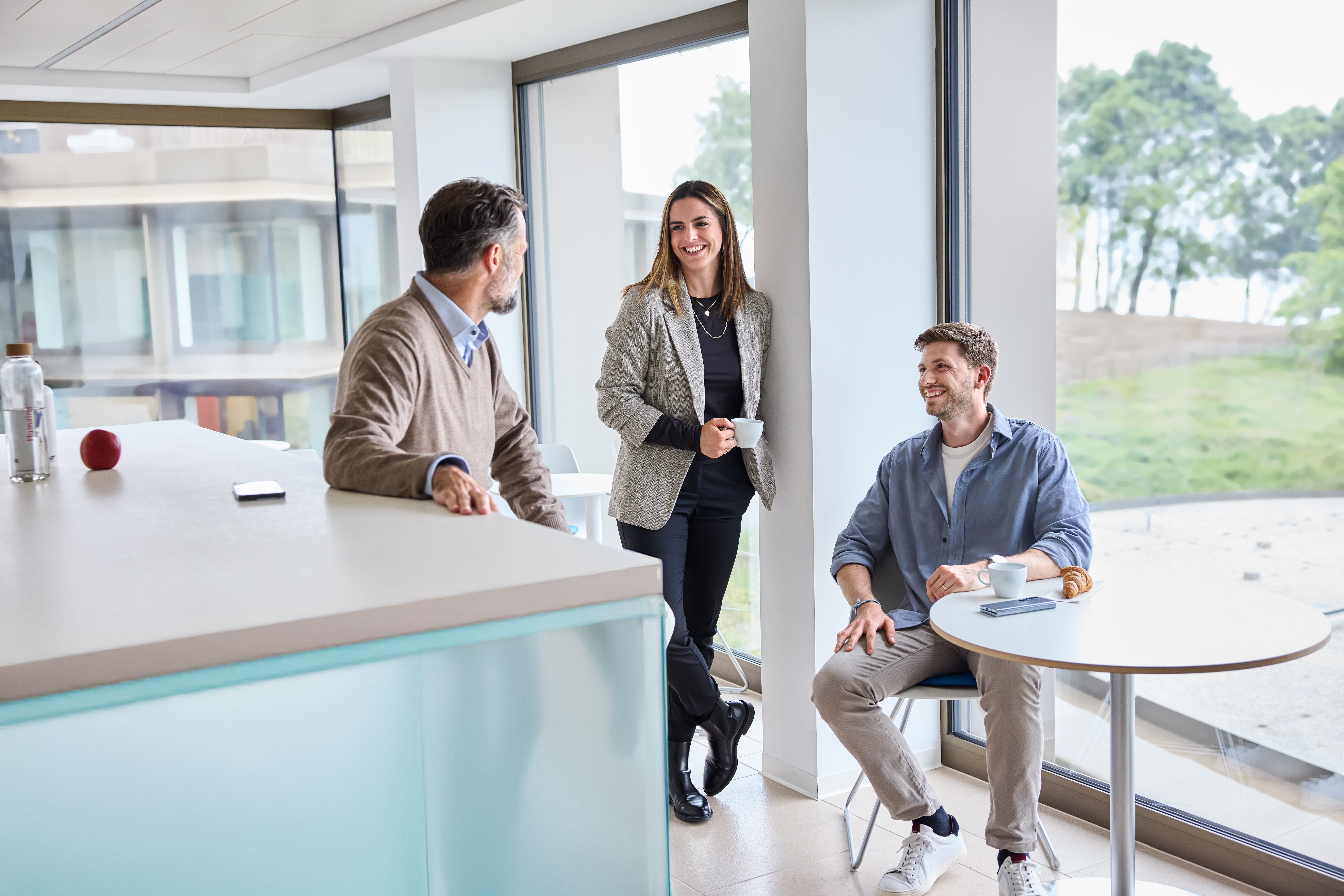 Mitarbeitende unterhalten sich im Pausenraum mit Aussicht ins Grüne