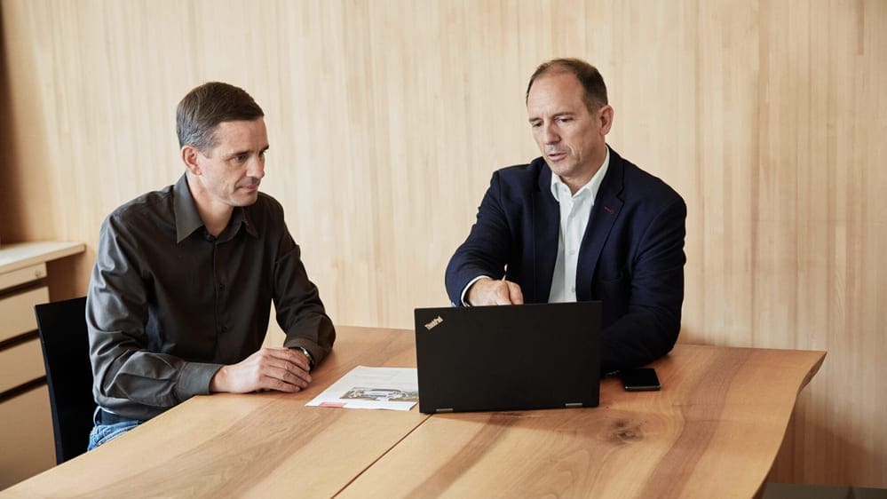 Zwei Männer diskutieren etwas am Laptop.