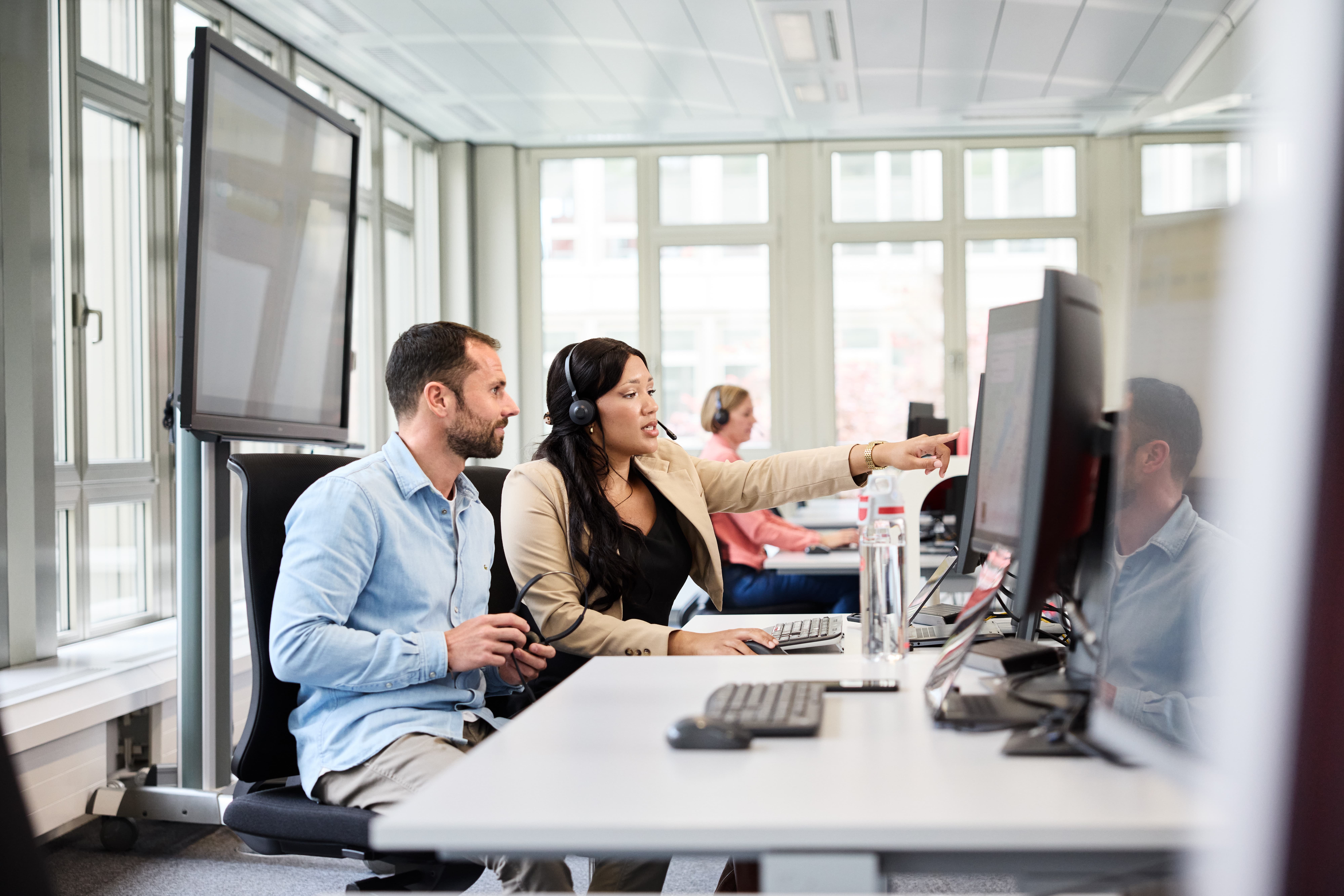 Mitarbeiterin zeigt Kollegen etwas auf dem Monitor
