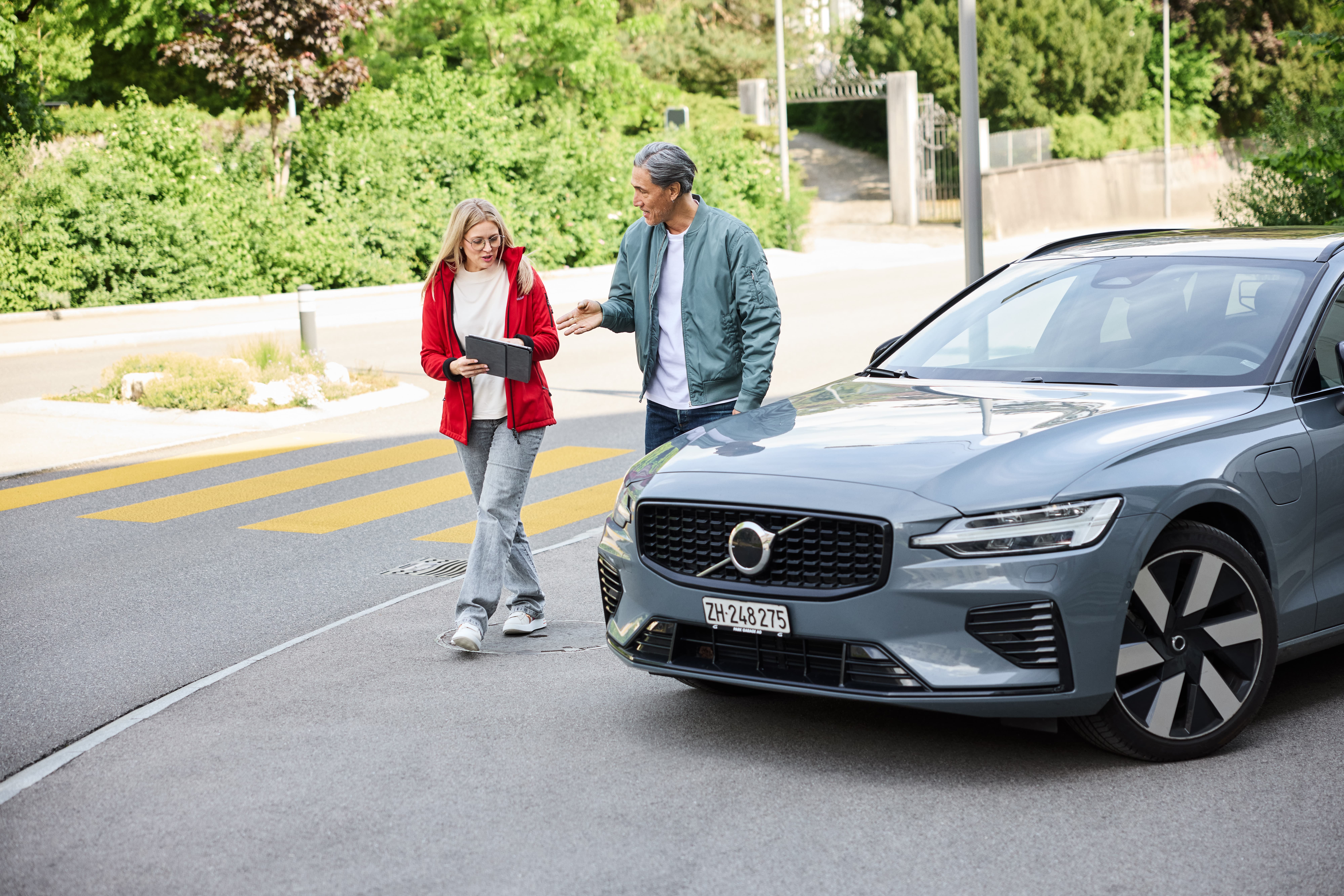 Versicherungsberaterin diskutiert mit ihrem Kunden vor einem Auto