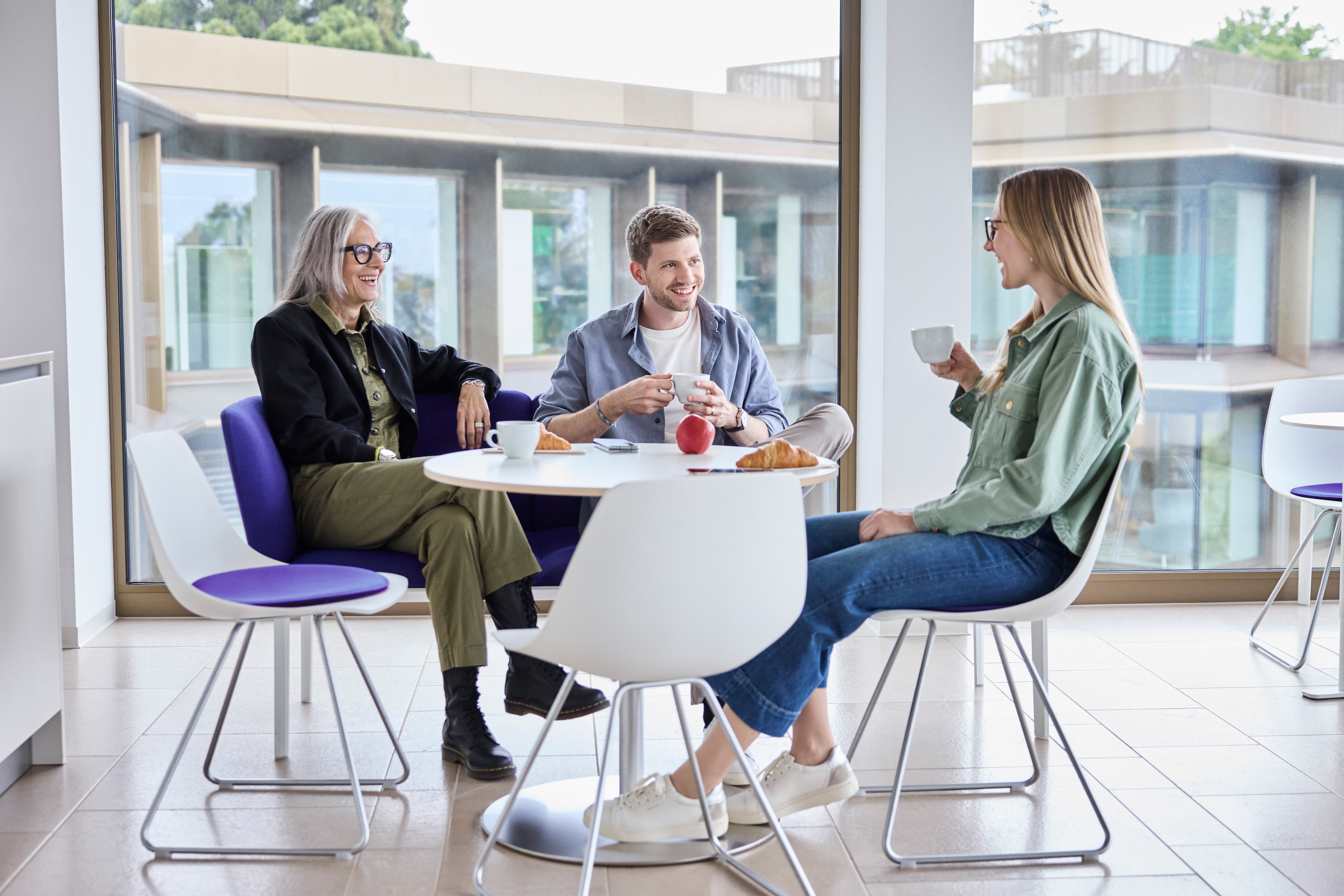 Mitarbeitende unterhalten sich bei Kaffee und Gipfeli