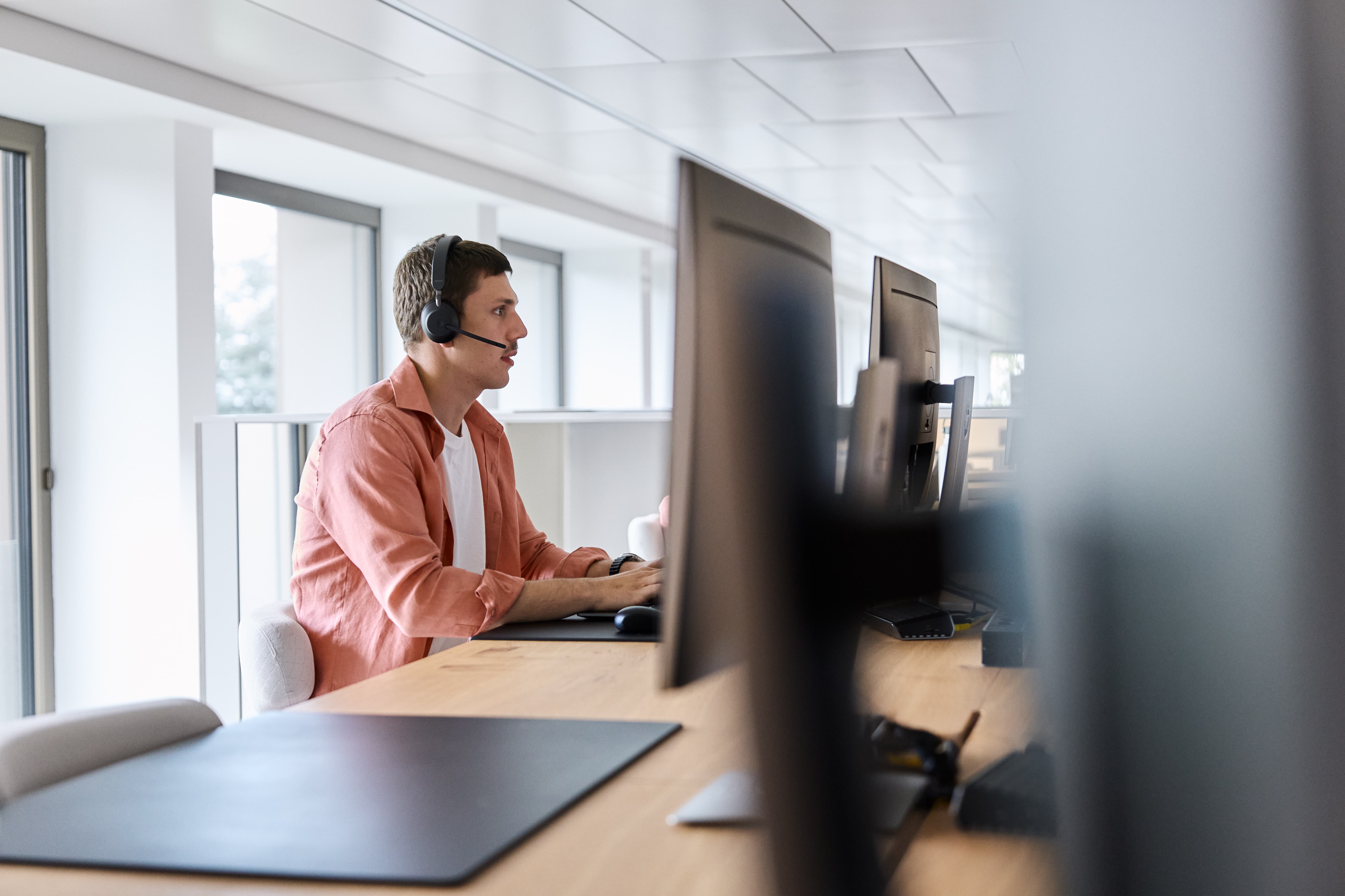 Mann telefoniert mit Headset am Computer