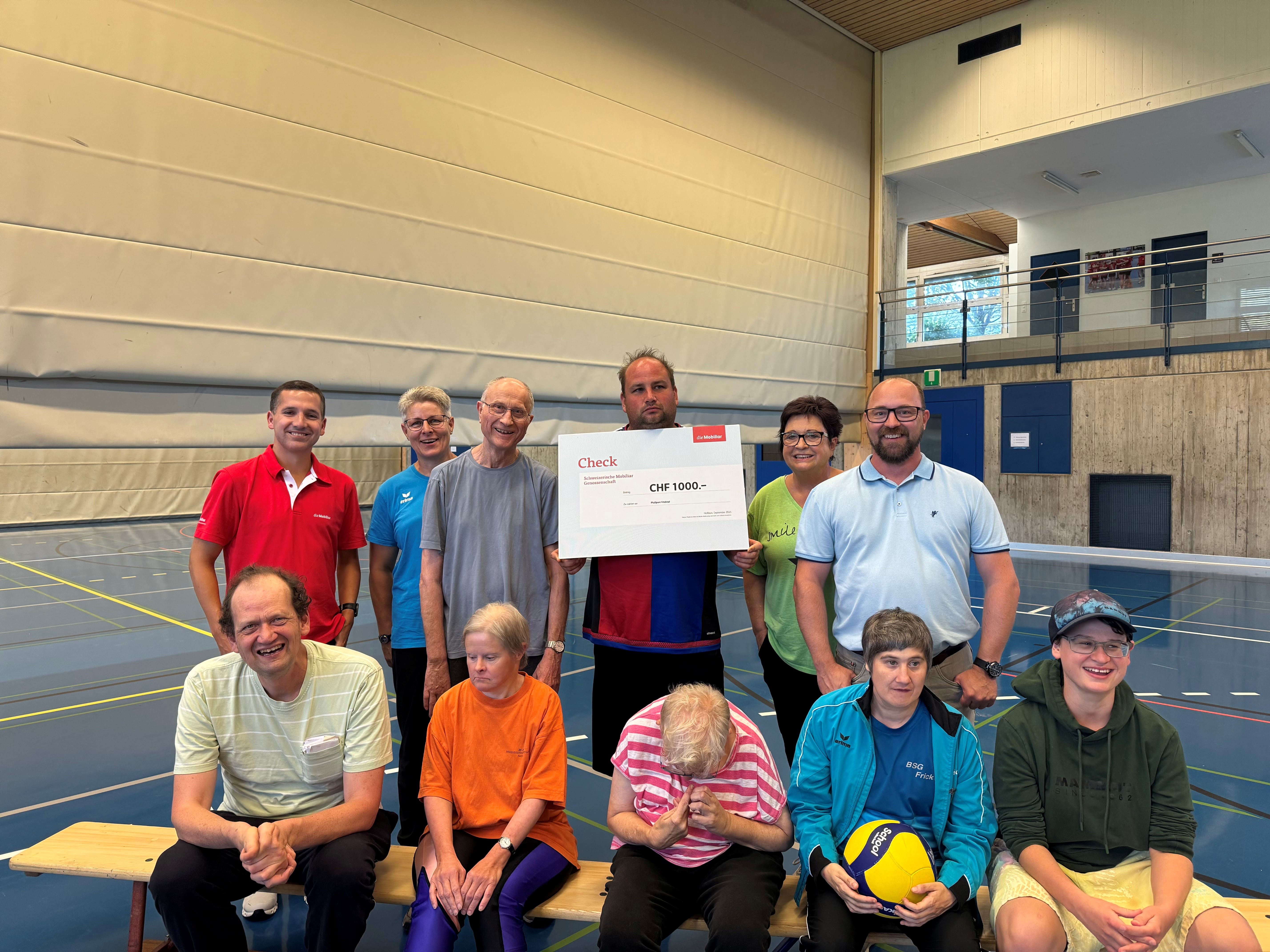 Eine Gruppe hält einen Mobiliar Check in einer Turnhalle.