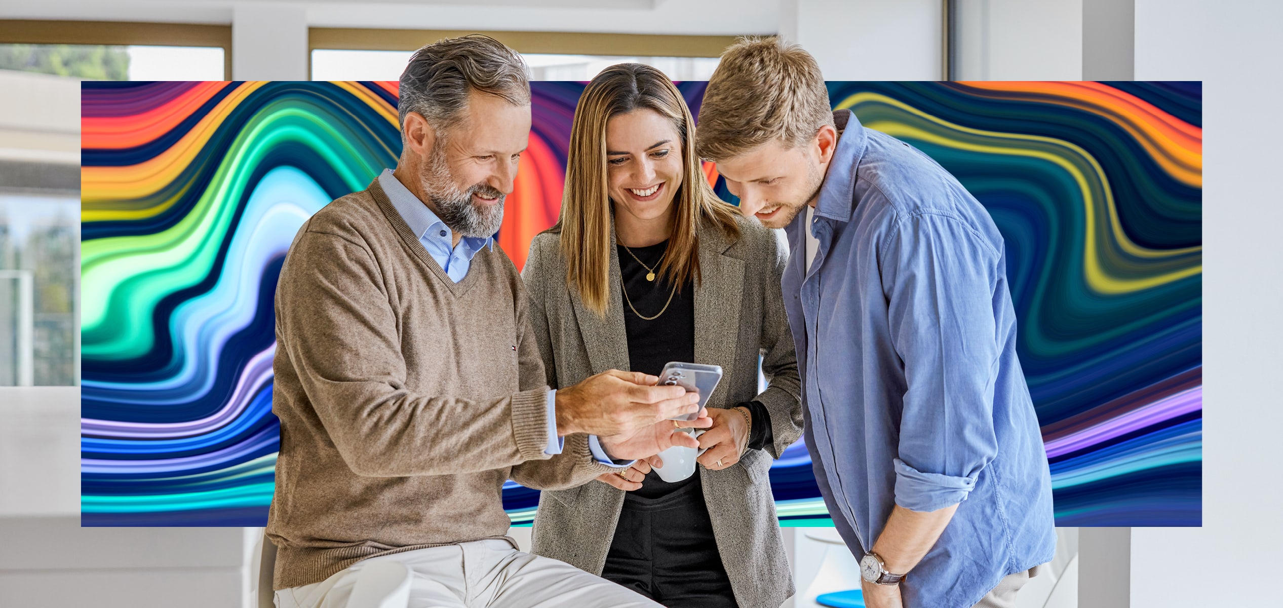 Drei Personen schauen auf ein Smartphone