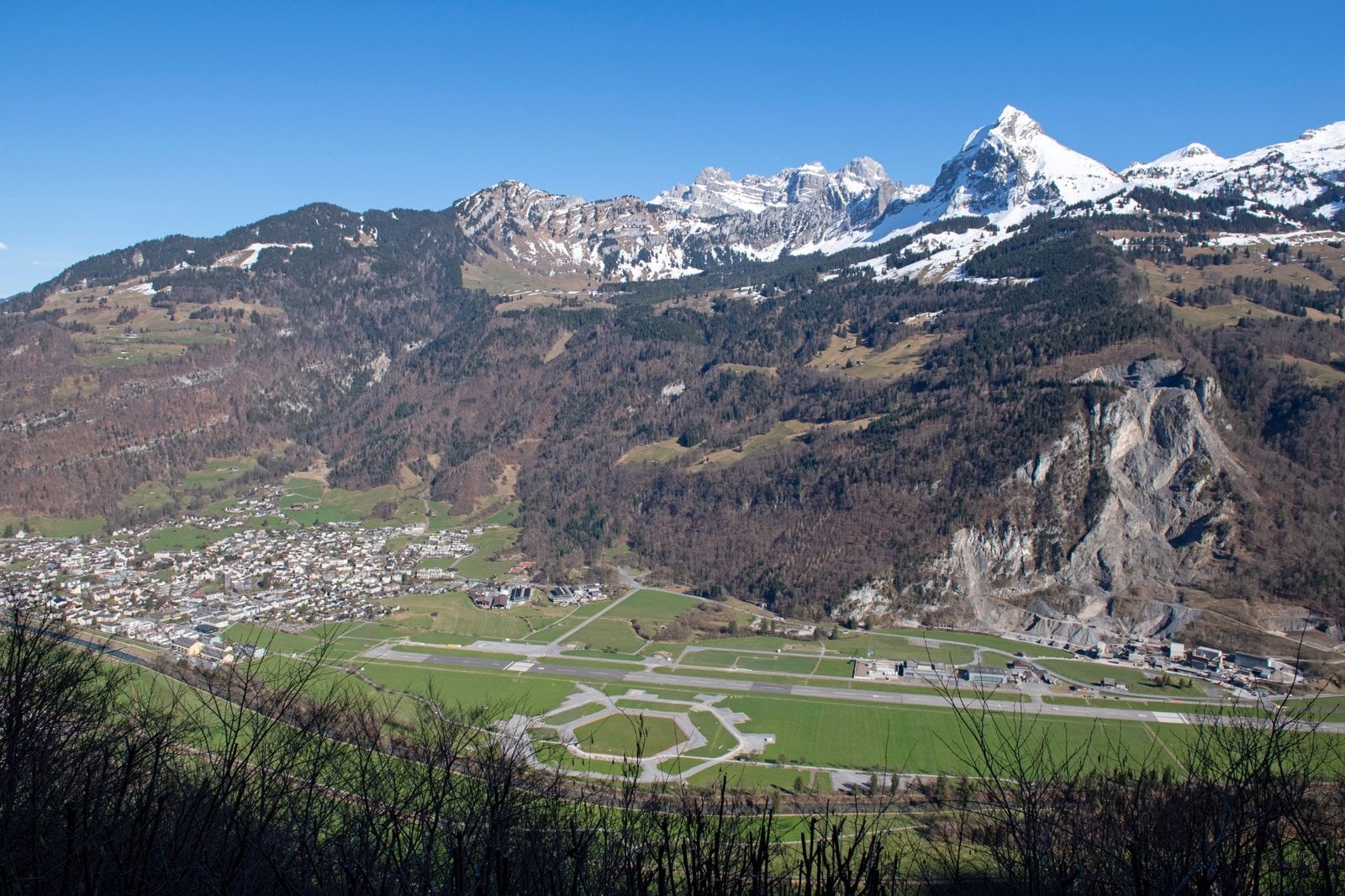 "Luftaufnahme des Festgeländes für das ESAF 2025 in Mollis mit Blick auf das Glarnerland und die schneebedeckten Alpen.