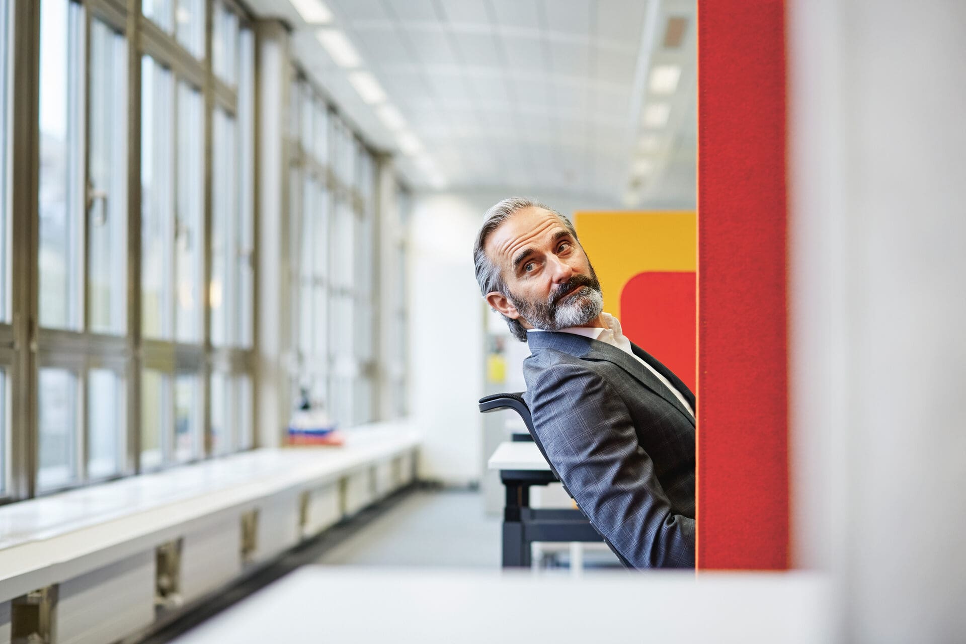 C’è un uomo seduto in un ufficio che guarda dietro.
