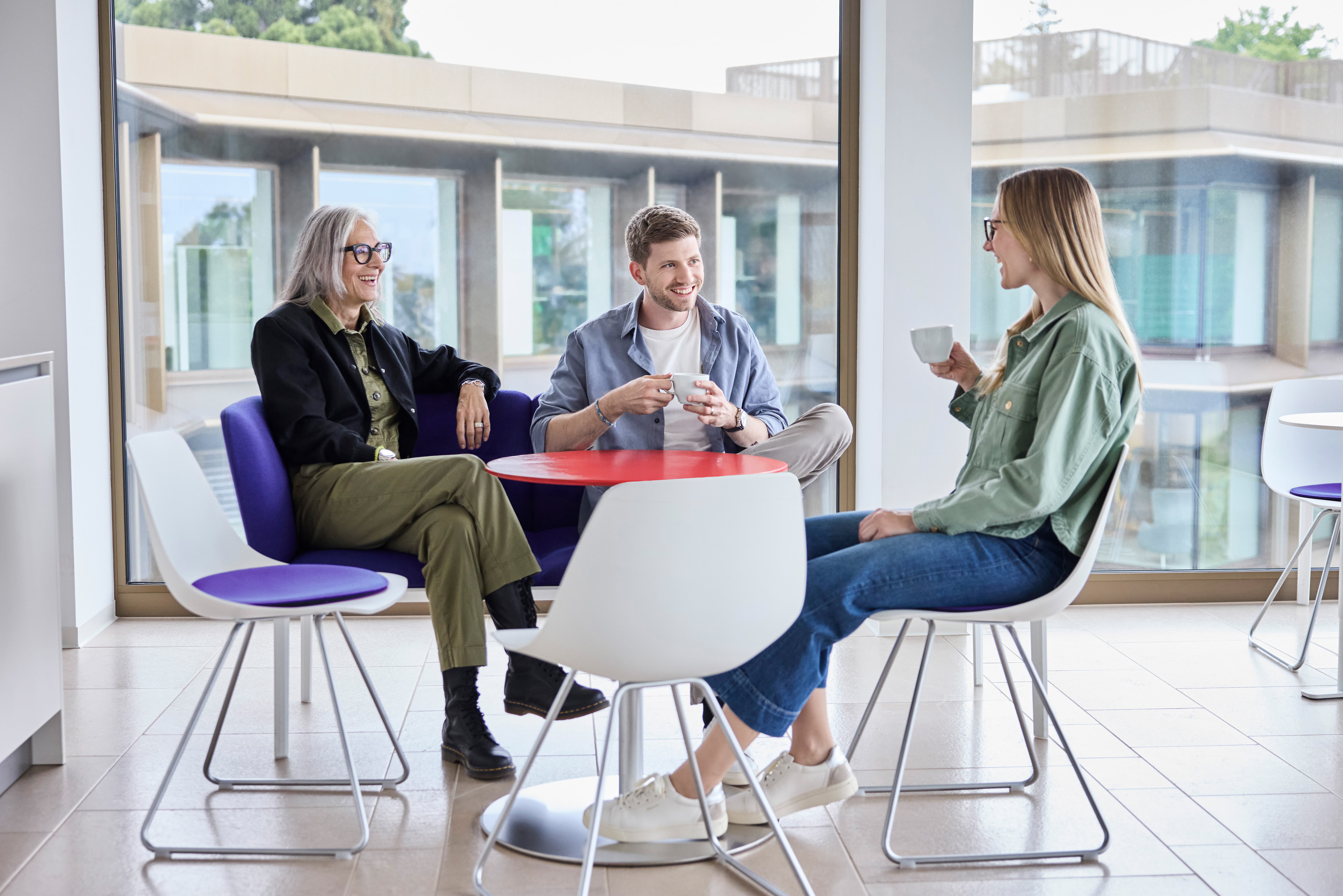 Drei Personen sitzen glücklich zusammen am Tisch