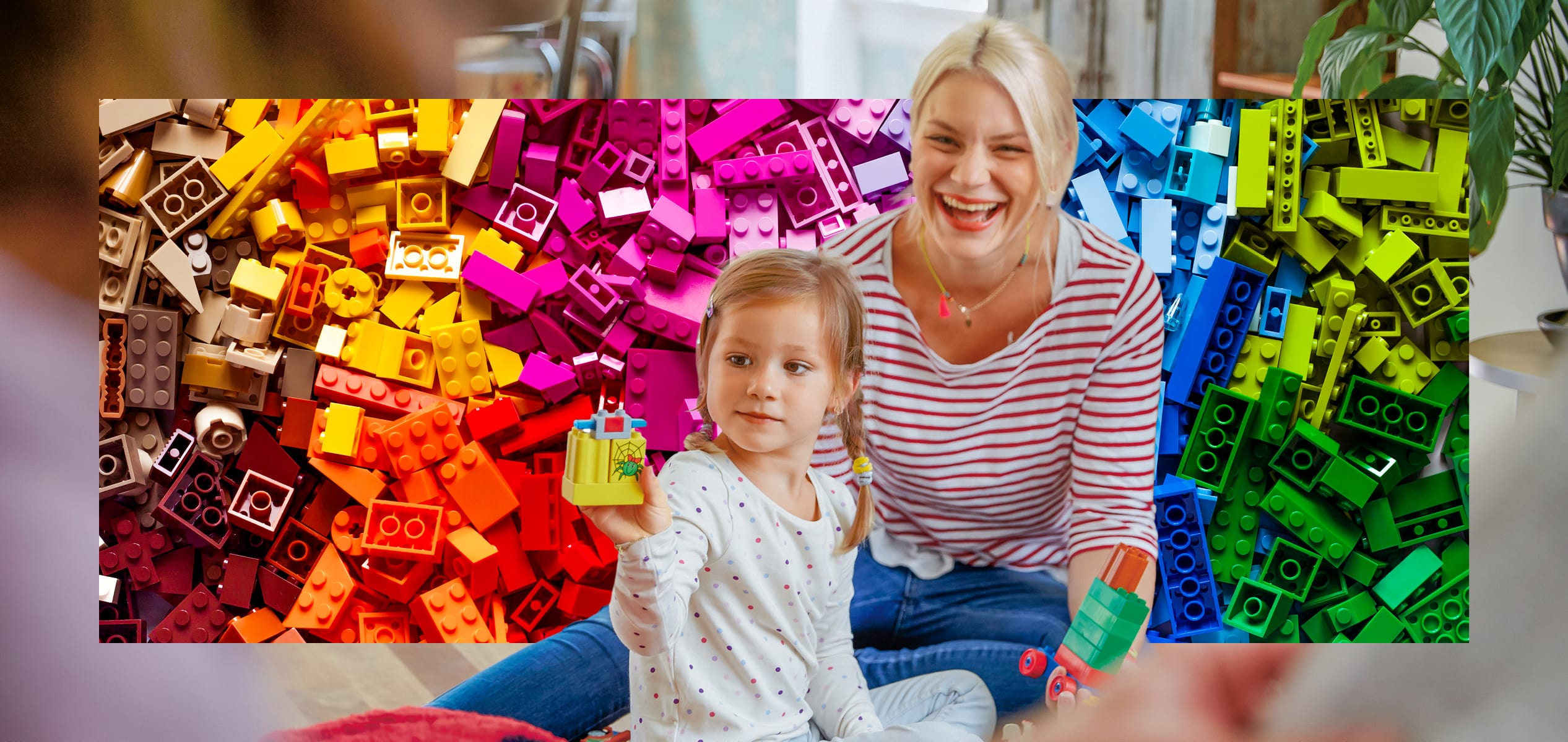 Kind spielt mit Bauklötzen, Mitarbeiterin lacht daneben