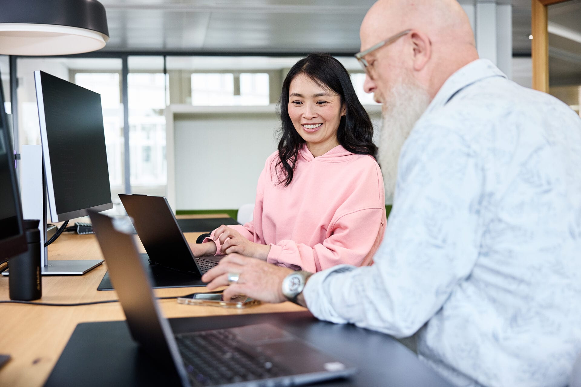 Mitarbeitende sitzen an den Laptops und tauschen sich aus
