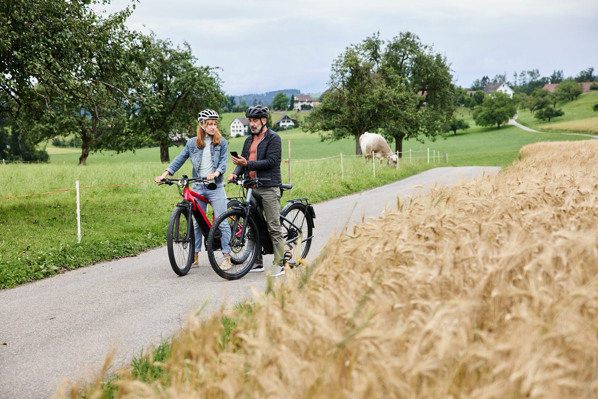 Ein paar sitzt auf dem Fahrrad und fährt einen Feldweg entlang