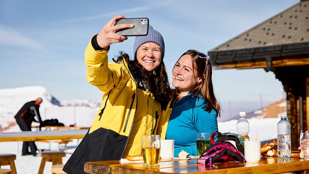 Zwei junge Frauen in einem Bergrestaurant am Selfie machen