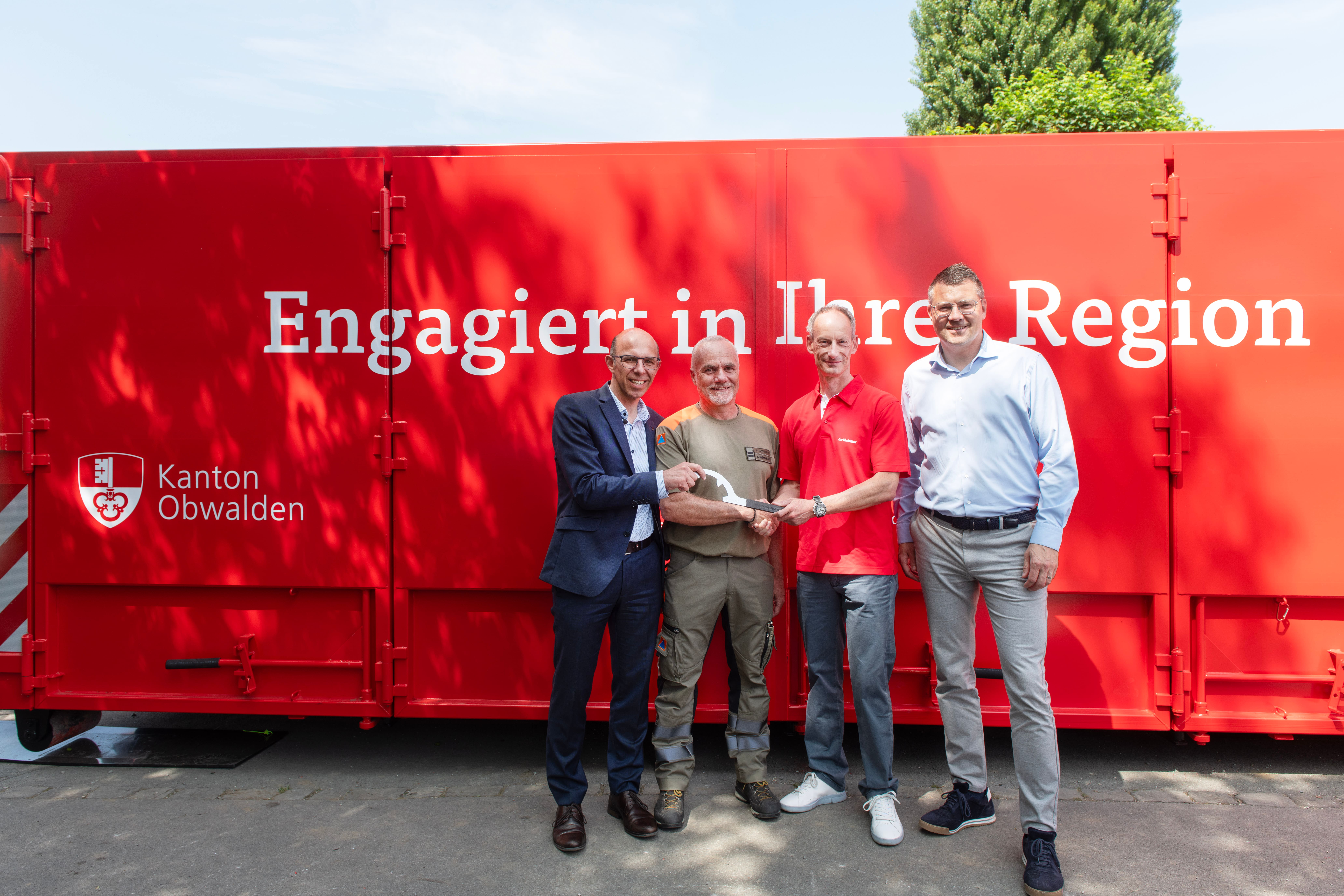 (v.l.n.r.) Regierungsrat Christoph Amstad und Leiter der Dienststelle Zivilschutz Bruno Odermatt freuen sich über den Container mit dem mobilen Hochwasserschutz, welcher die Mobiliar – hier Roland Arnold (Generalagent der Mobiliar Obwalden und Nidwalden) und Philippe Genoud (Leiter Schaden) – dem Kanton überreicht hat.