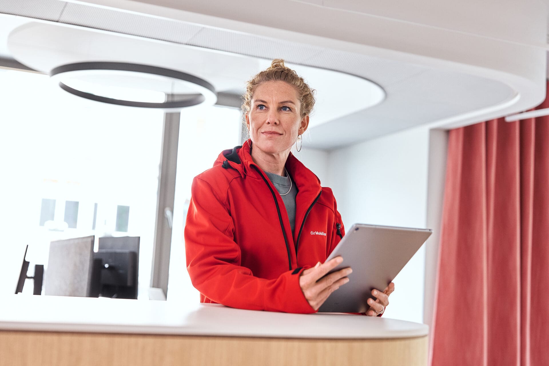Mitarbeiterin ist am Stehpult mit Tablet in der Hand