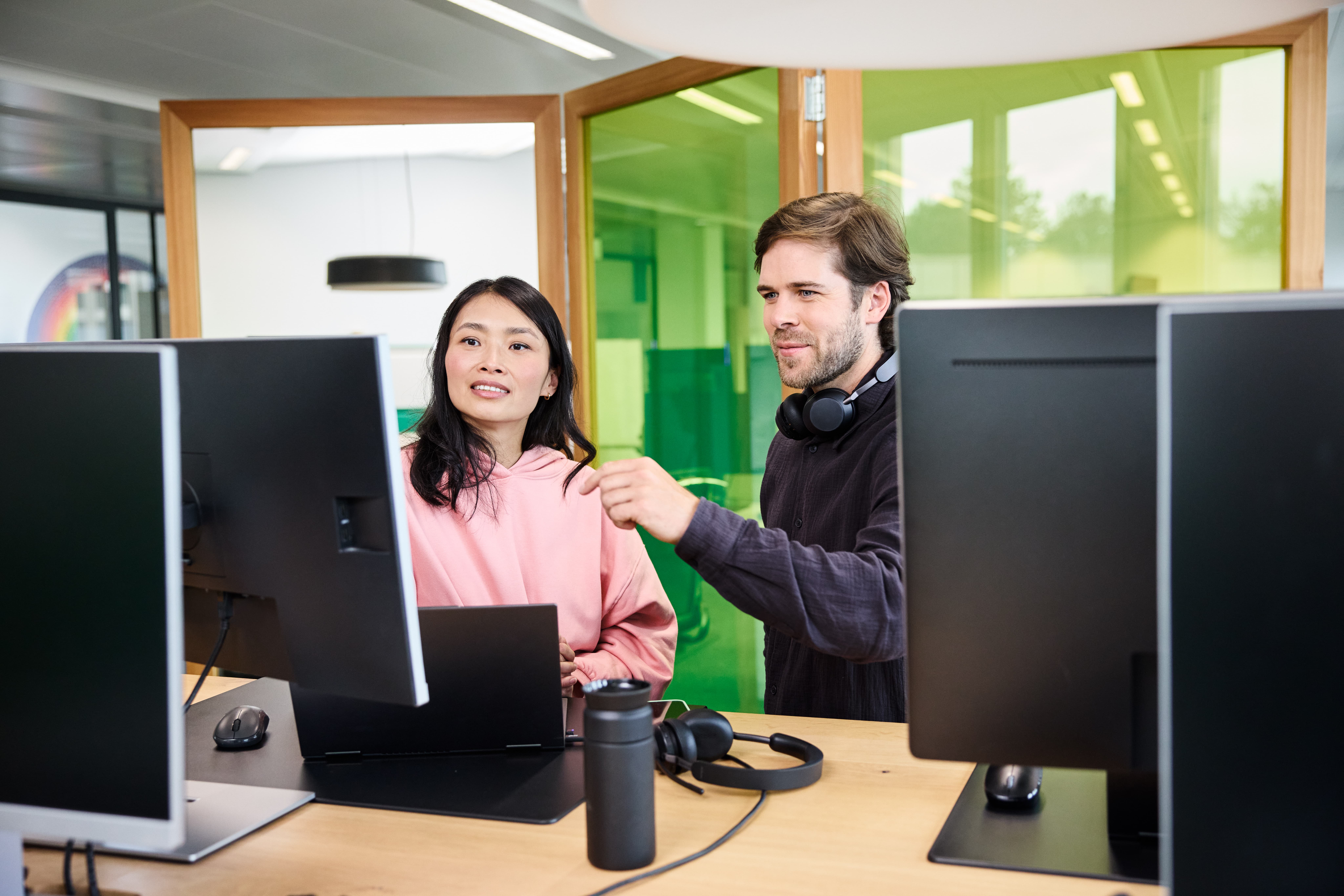 Mitarbeiter zeigt Kollegin etwas am Monitor