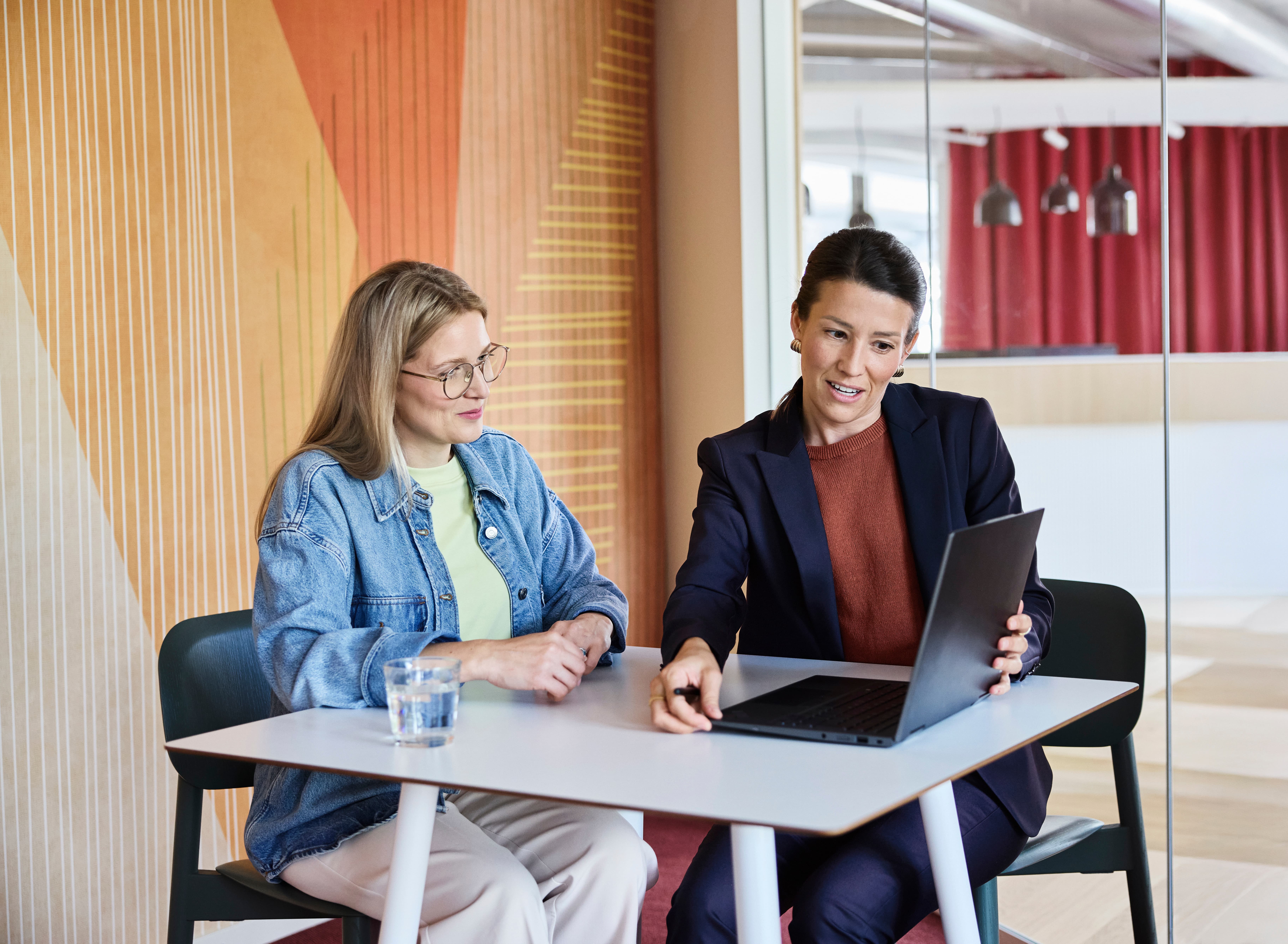 Zwei Frauen schauen auf einen Laptop.