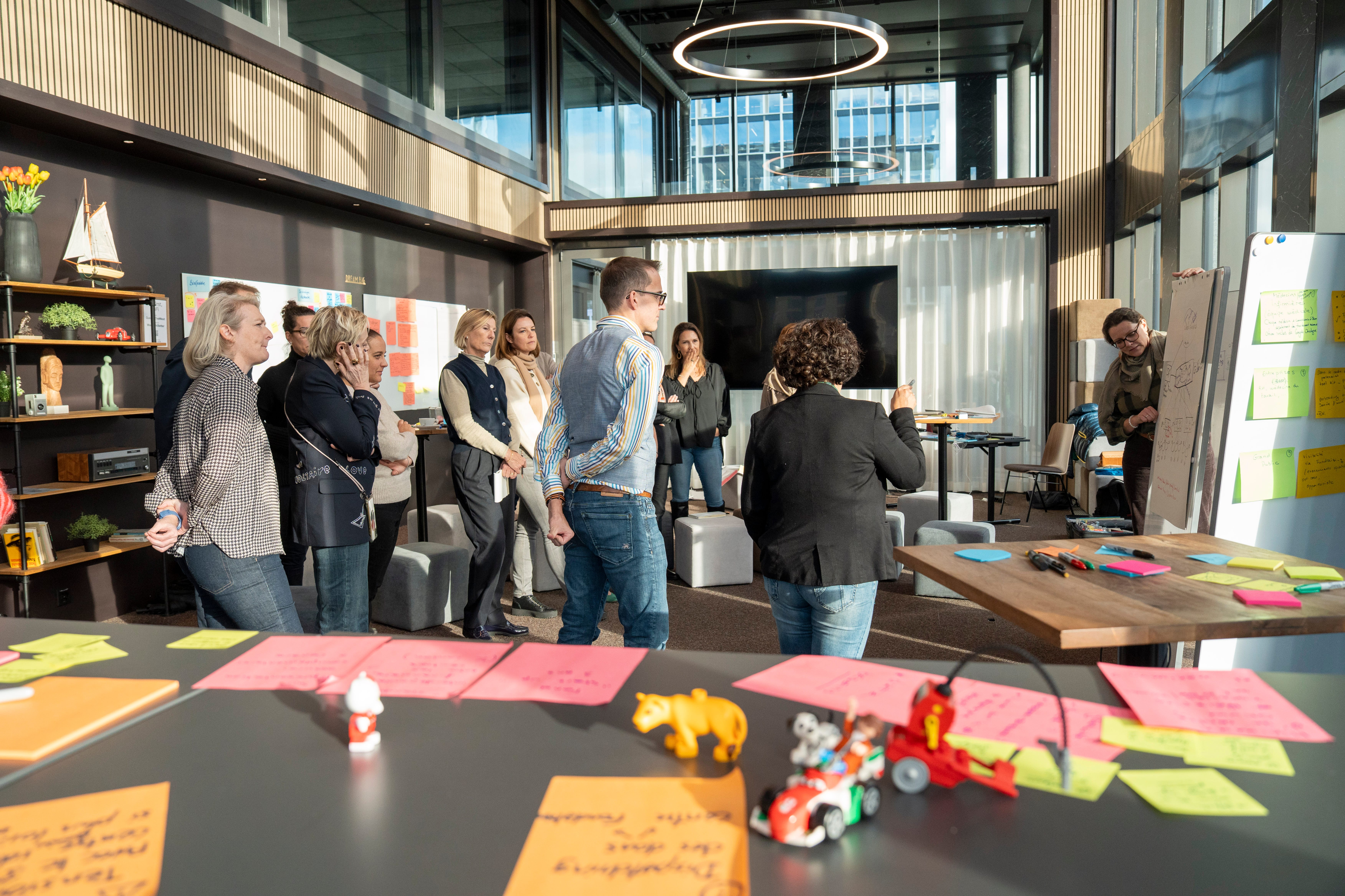 Eine Workshopgruppe steht im Raum und bespricht gemeinsam ihre Ideen. Im Vordergrund liegen Post-its.