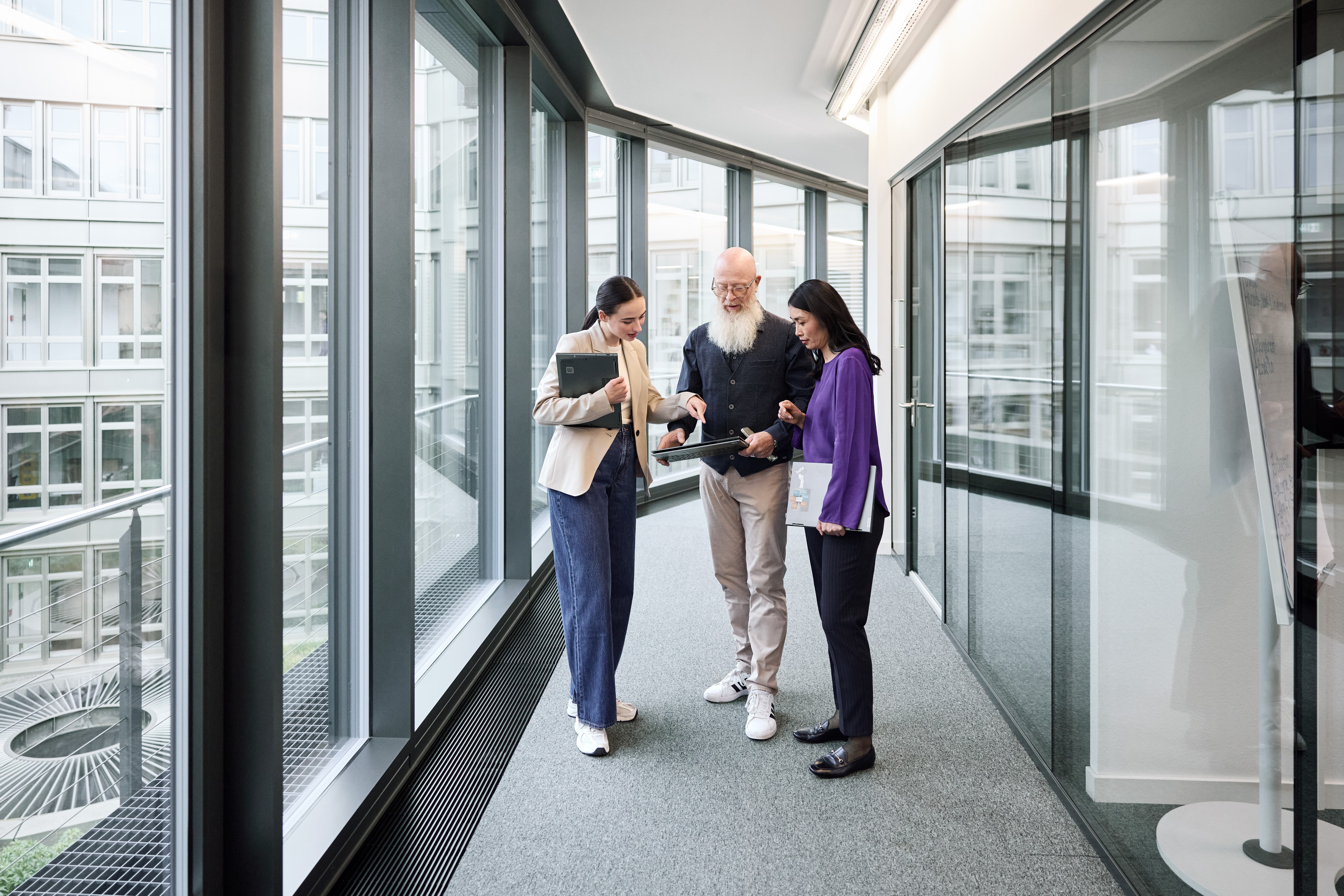 Drei Mitarbeitende halten ein Gespräch in einem Gang
