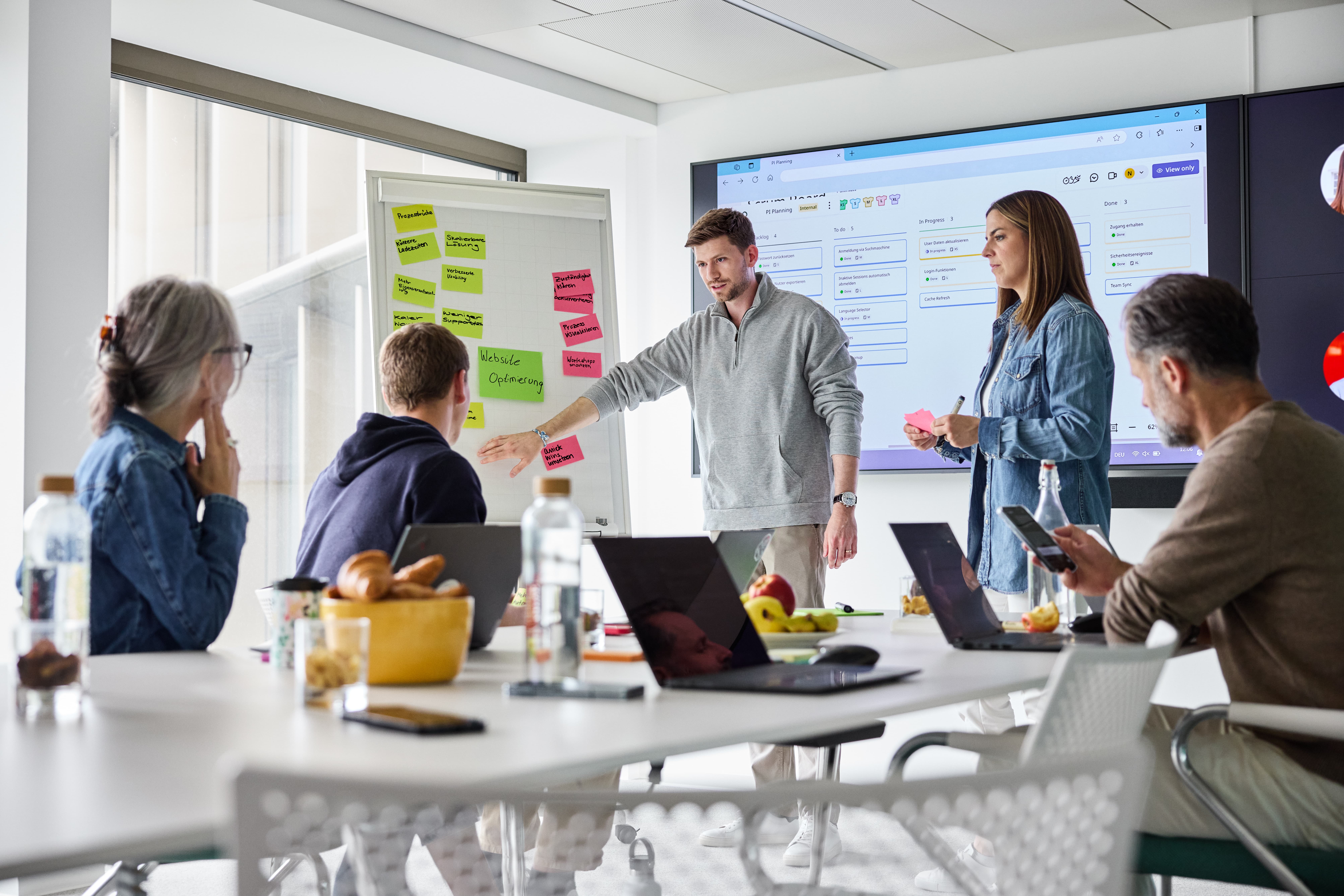 Mitarbeitende beim Teamwork mit Post-its und Screen