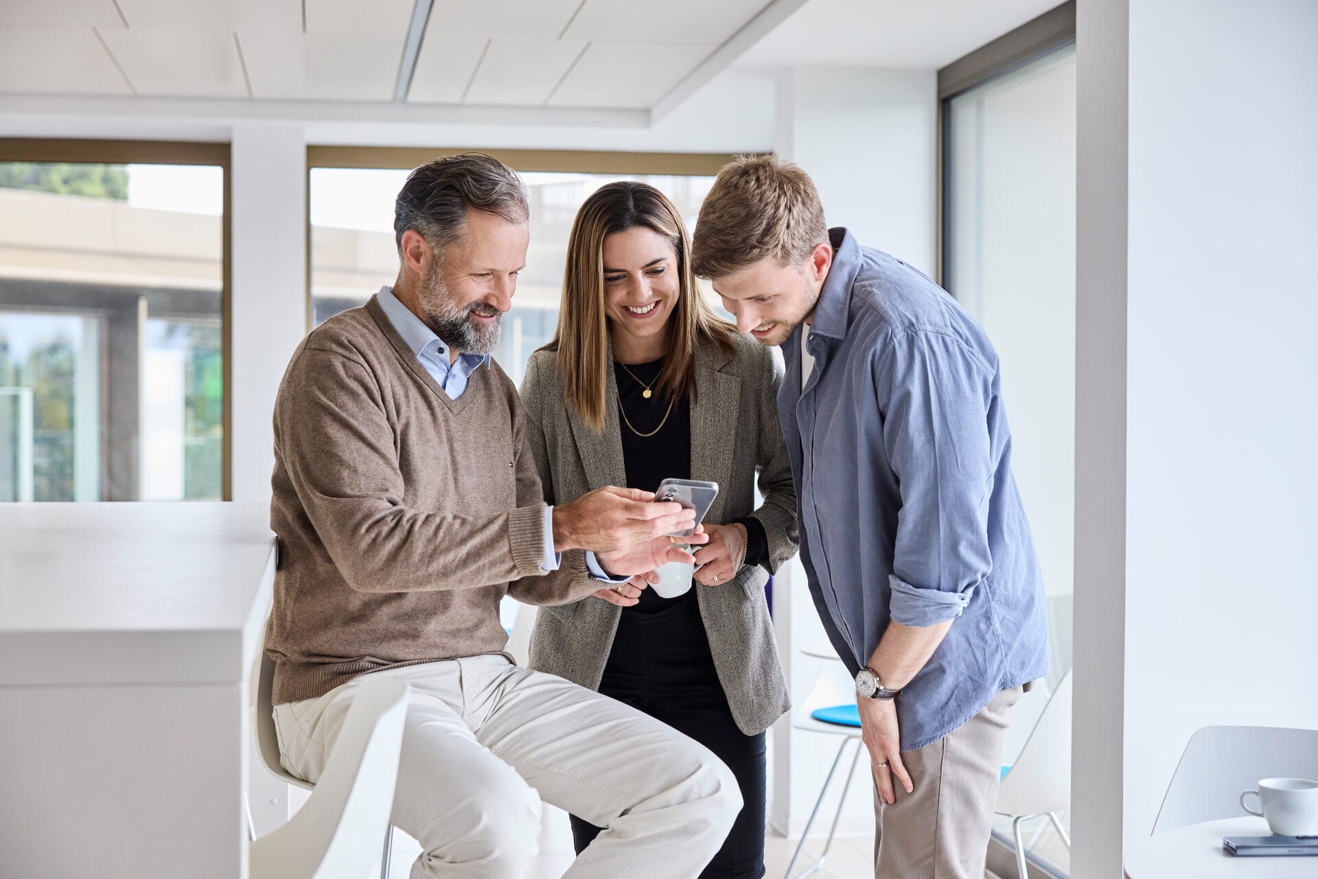 Mitarbeitende schauen etwas auf einem Smartphone an