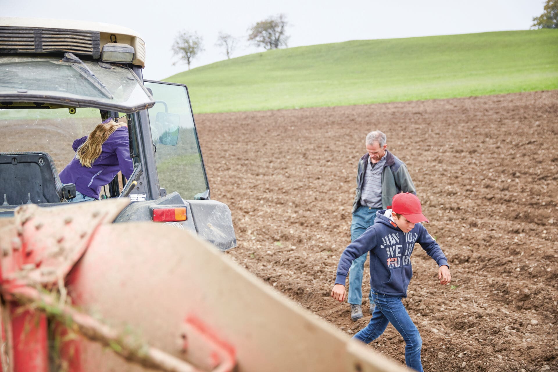 Familie arbeitet mit Kinder auf dem Feld mit einem Traktor