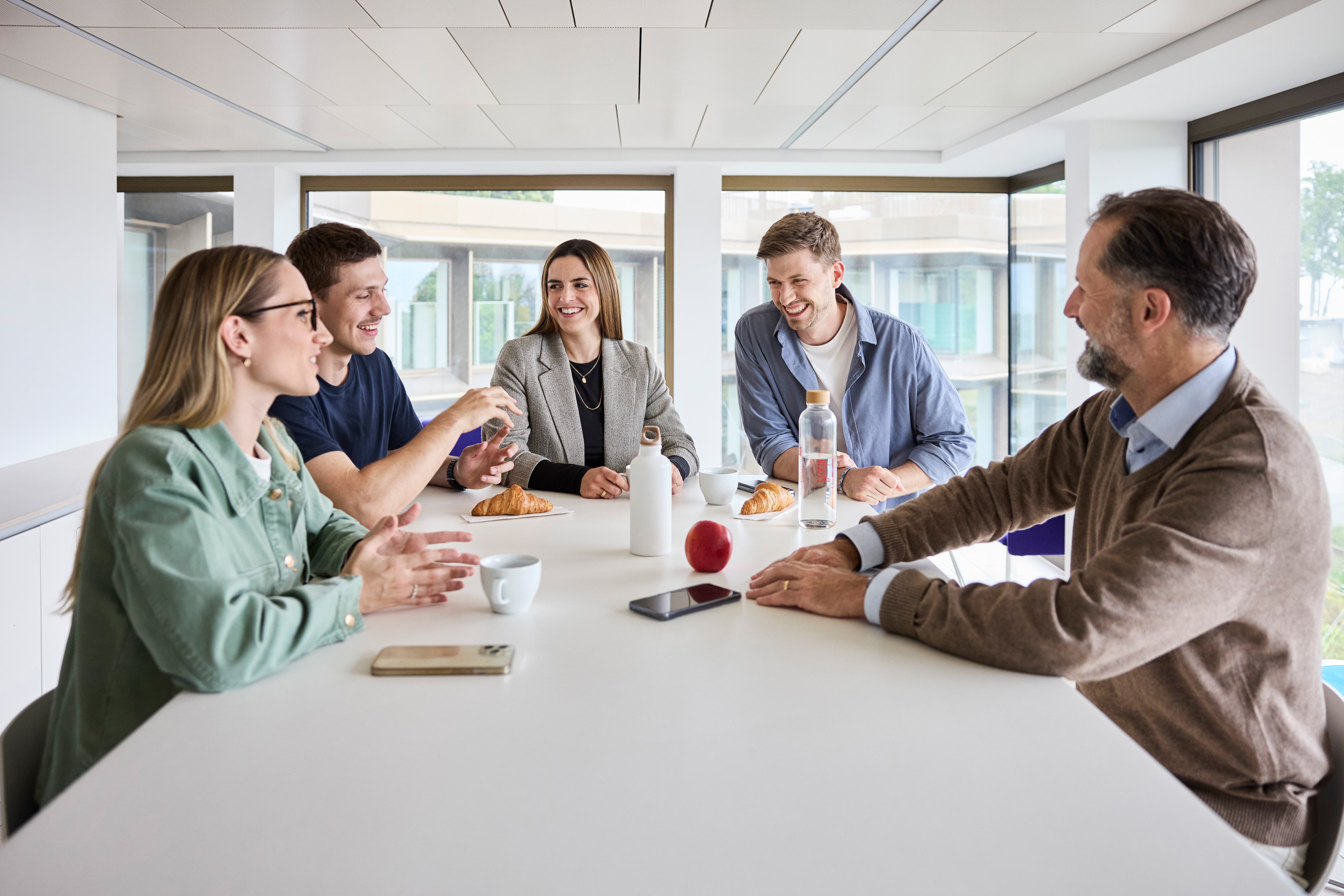 Mitarbeitende lachen zusammen in der Pause