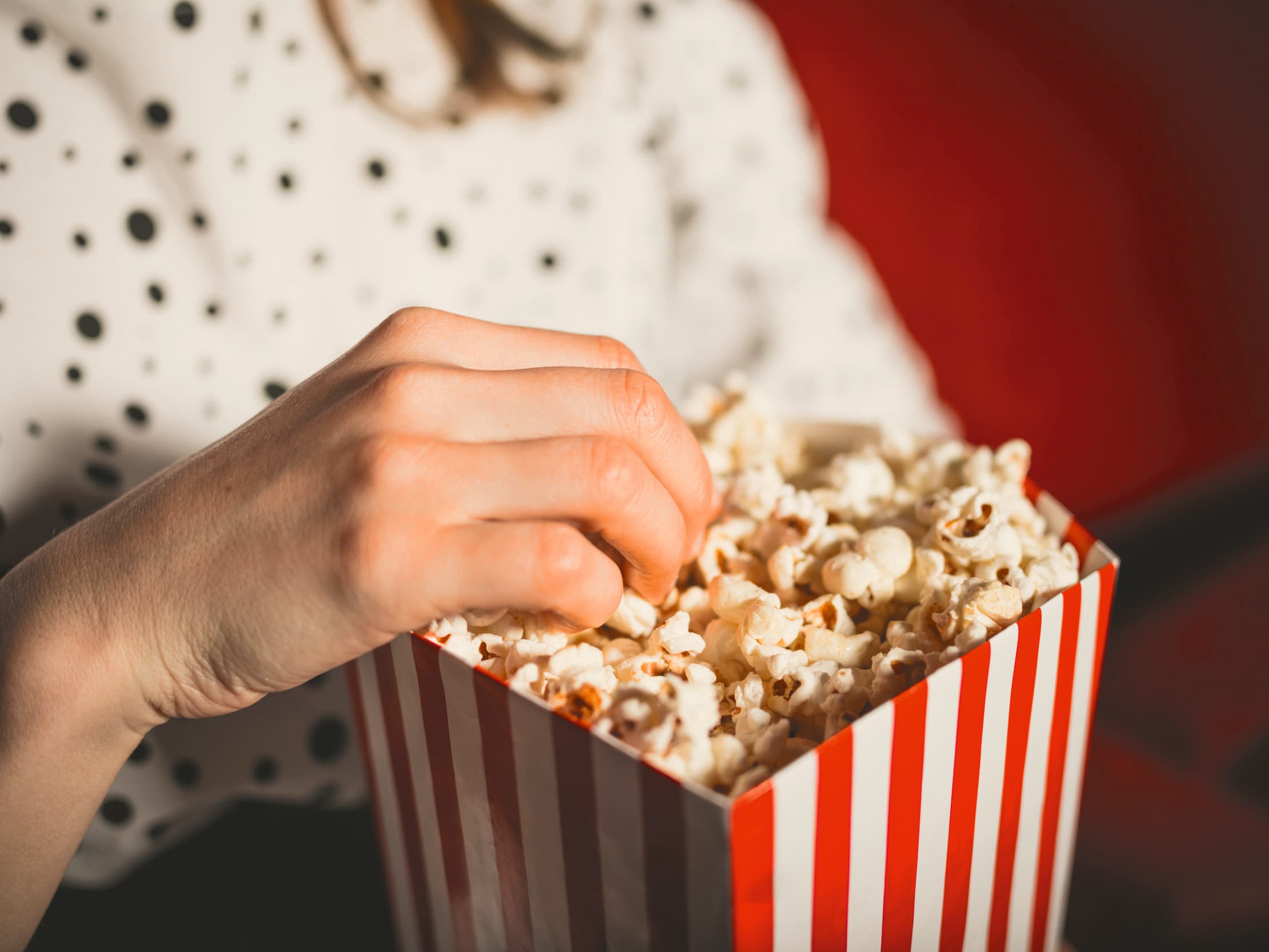 Frau isst Popcorn im Kino