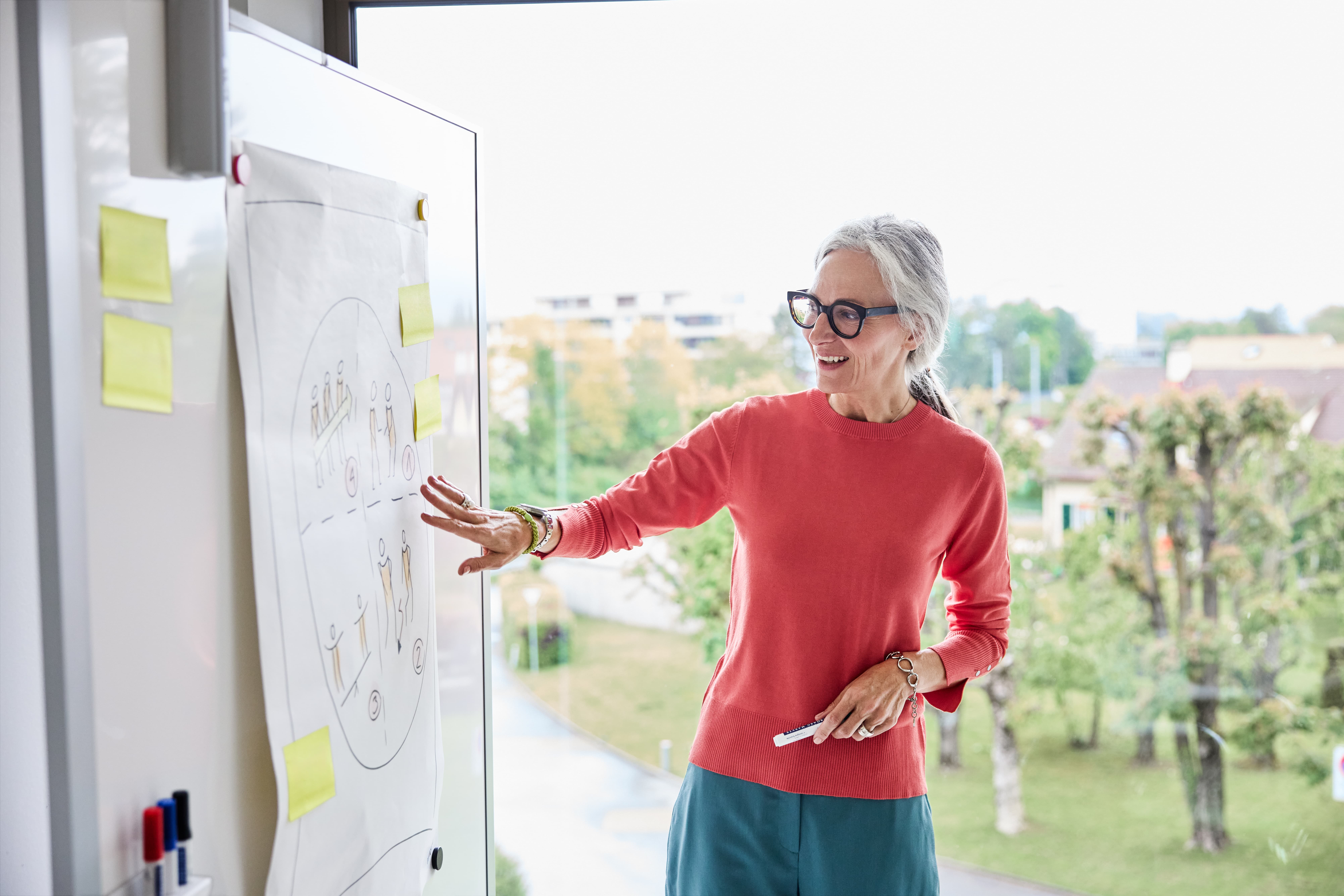 Mitarbeiterin kommentiert Skizzen auf dem Whiteboard  