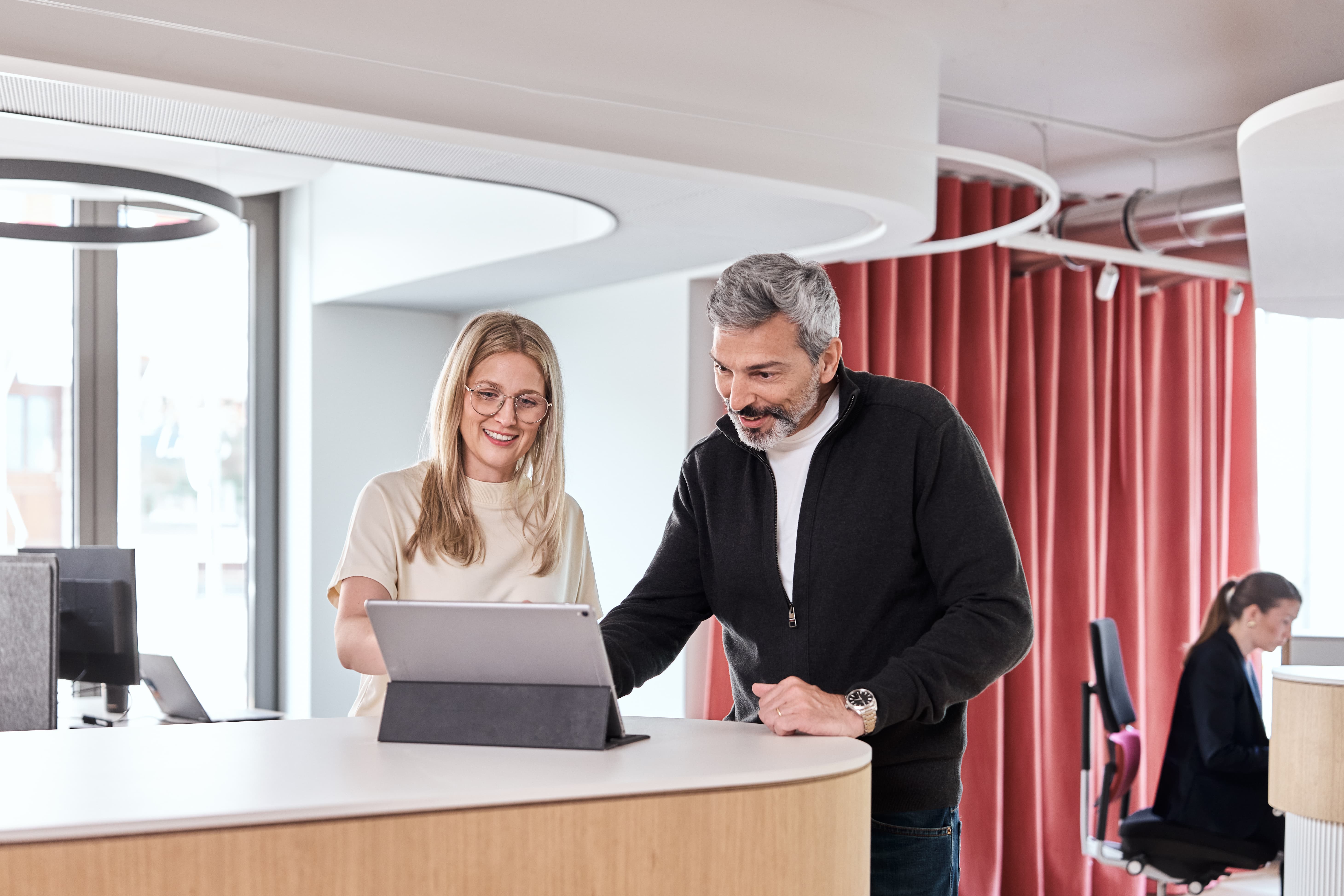 Zwei Mitarbeitende arbeiten an einem Tablet an Stehpult
