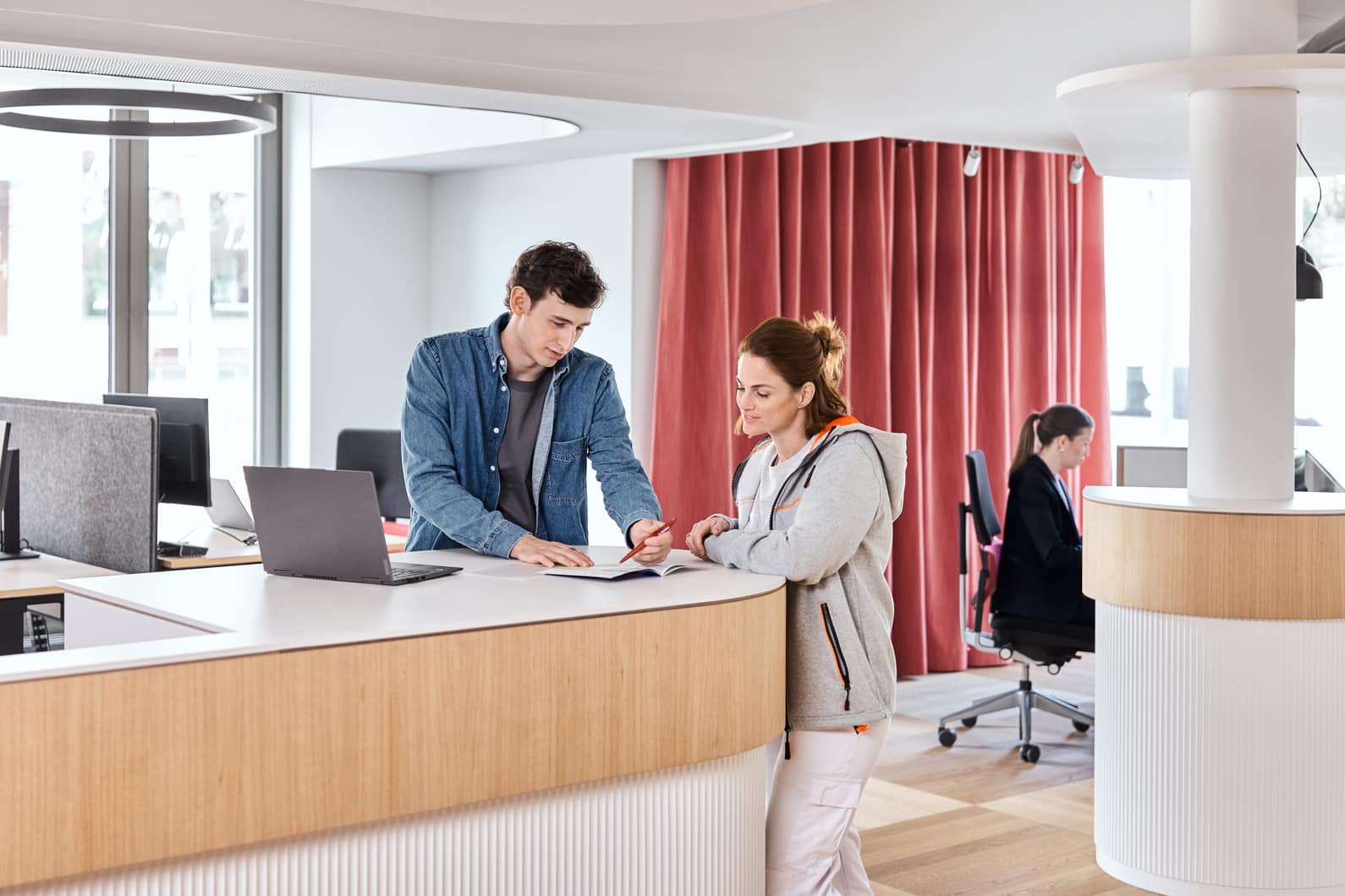 Mitarbeitende besprechen sich am Stehpult