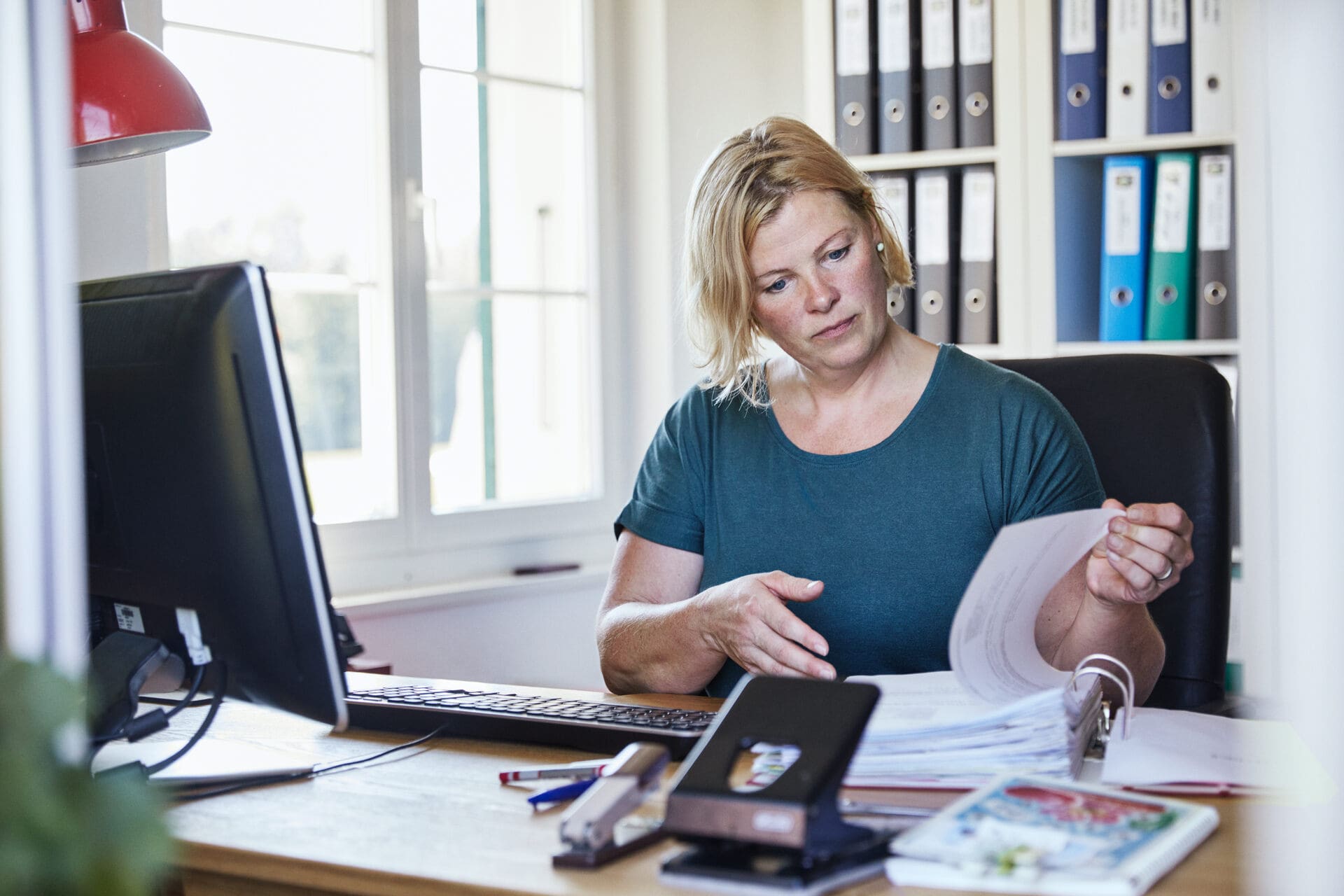 Une femme lit un document au bureau.