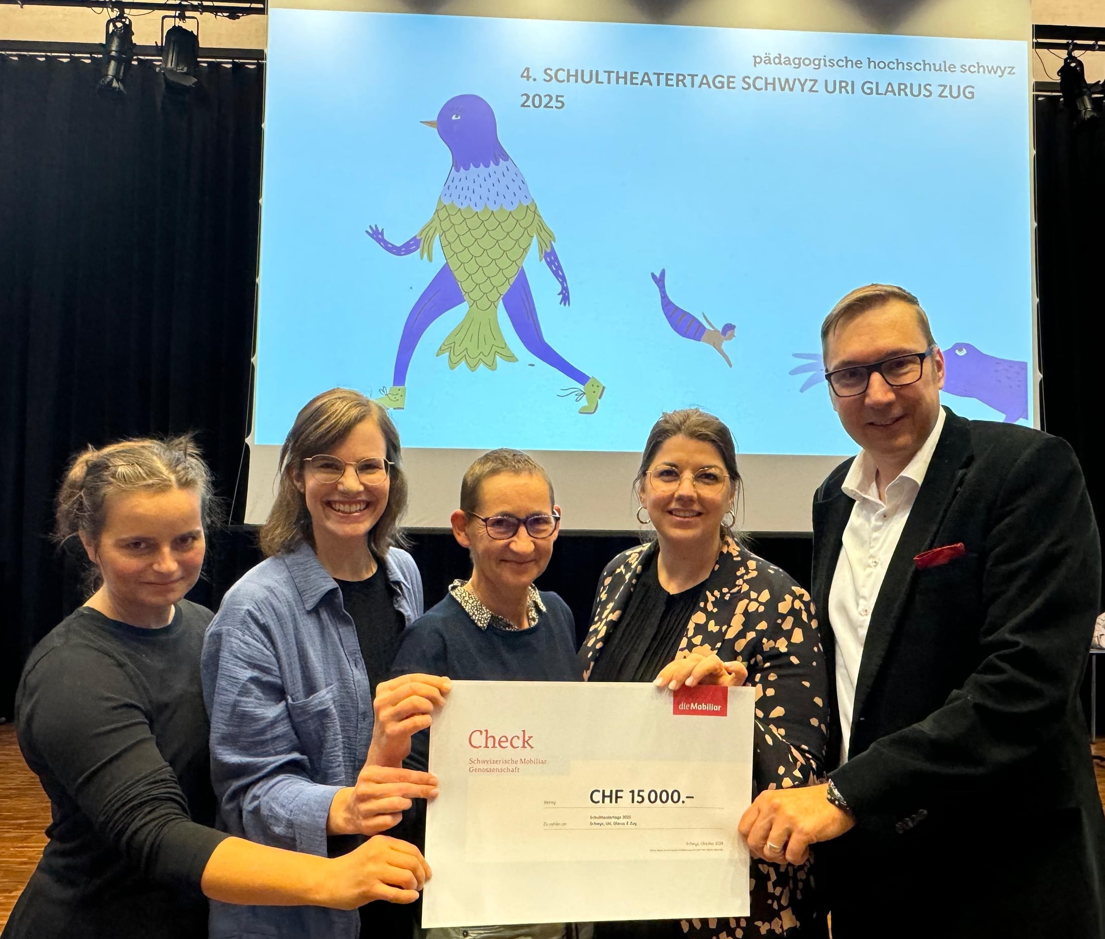 5 Personen halten einen Mobiliar Check von 15'000