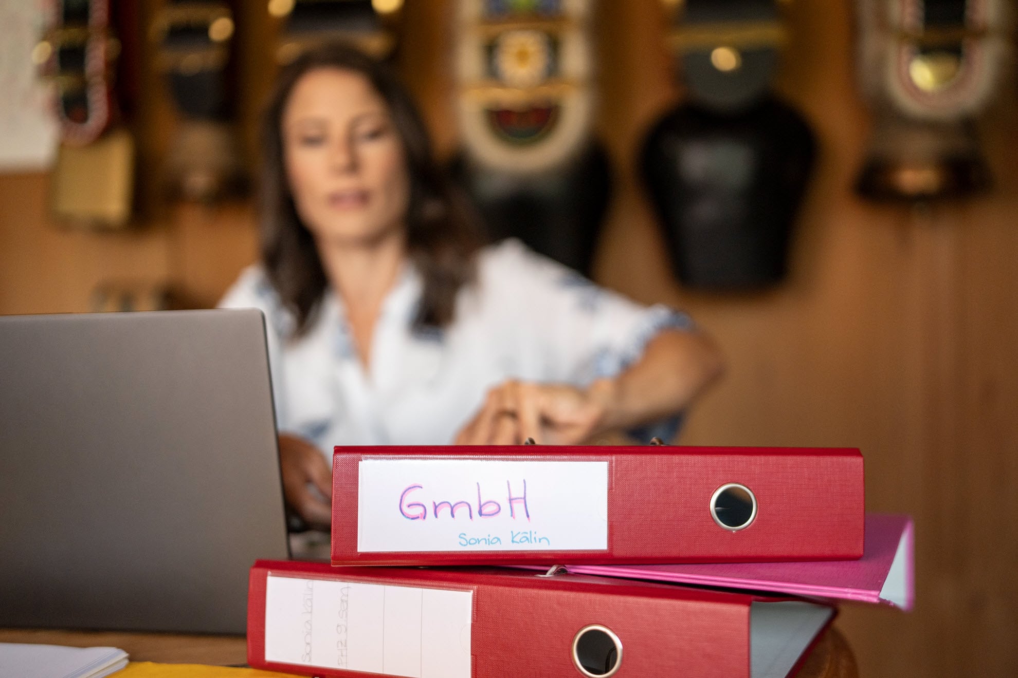 Sonia Kälin sitzt an ihrem Arbeitstisch und blickt auf ihre Unterlagen. Im Vordergrund ein Ordner, der mit GmbH angeschriebe ist.